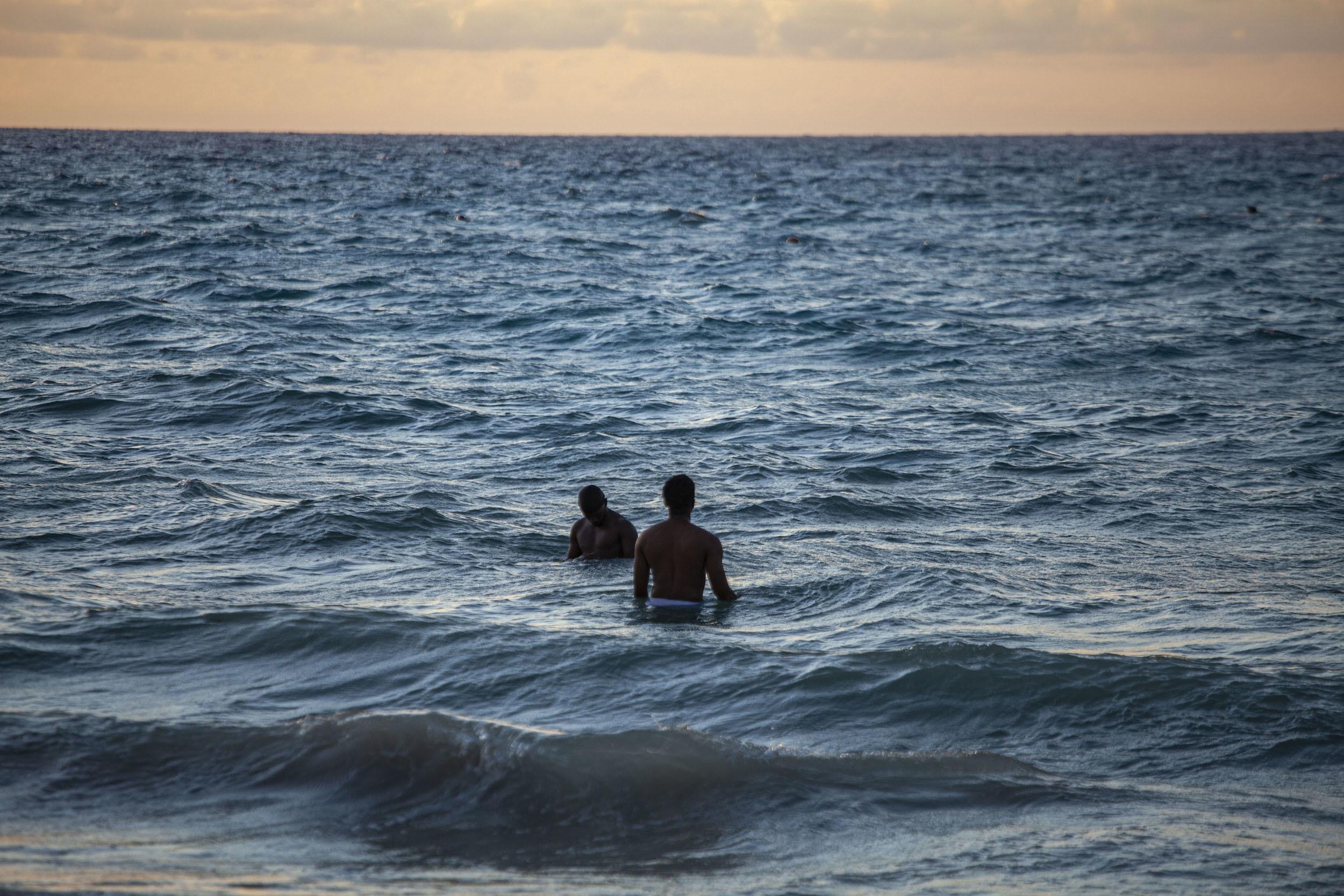 Comorian men swimming at dusk at Itsandra Beach Moroni Comoros