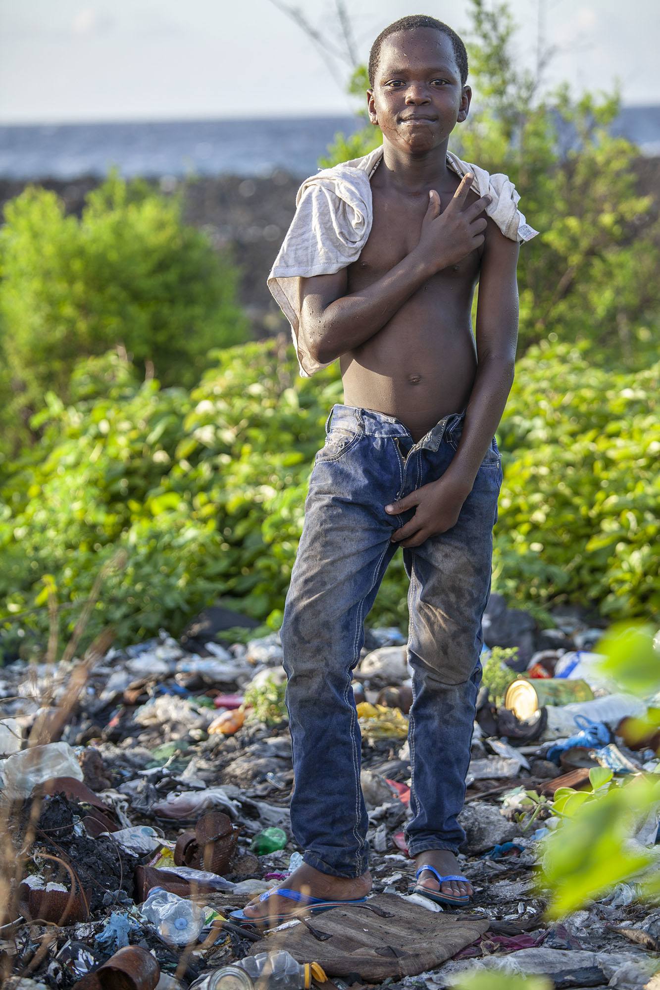 Teenage Comorian boy on lava rocks and trash in Moroni Comoros