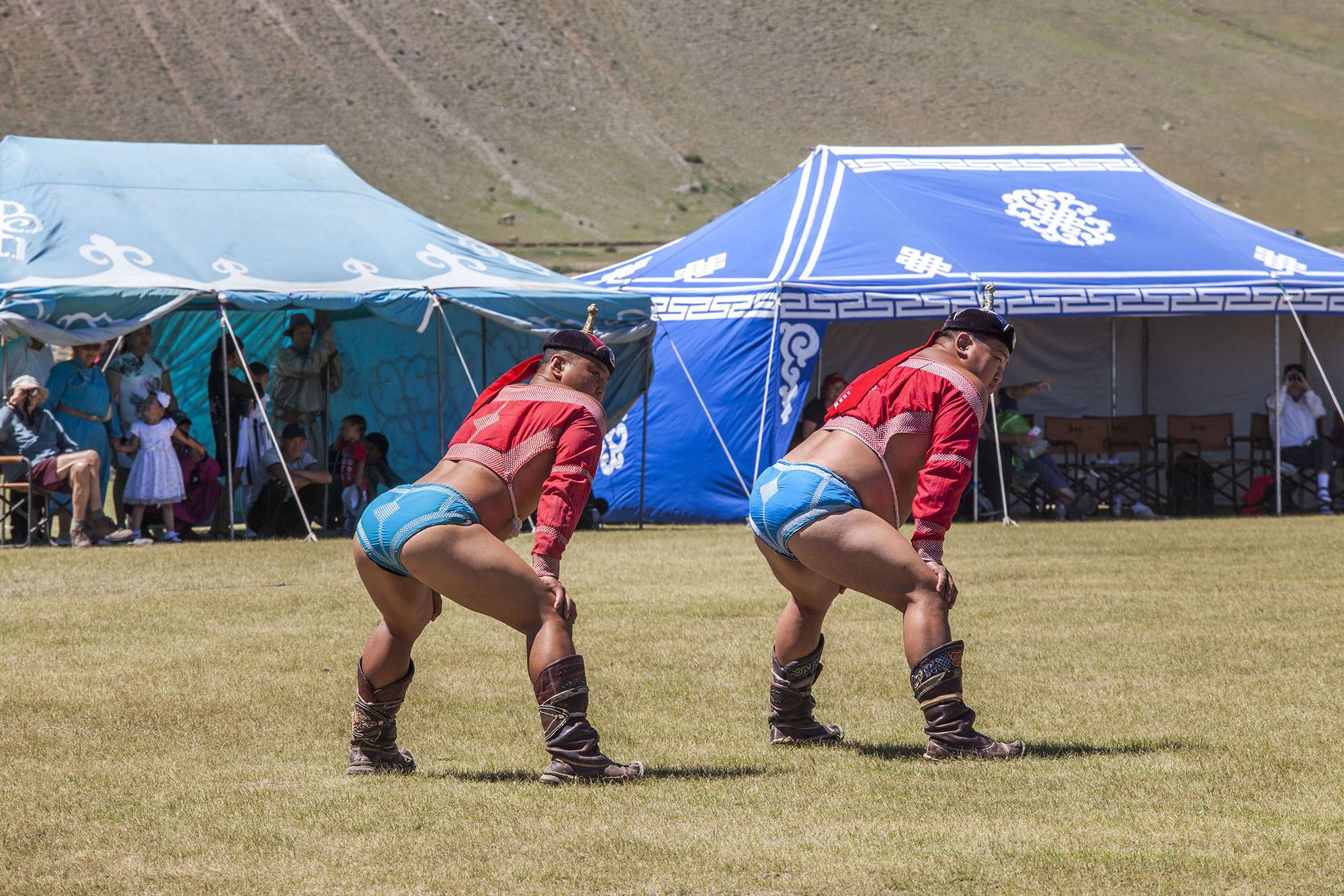 Mongolian wrestlers stretching on field