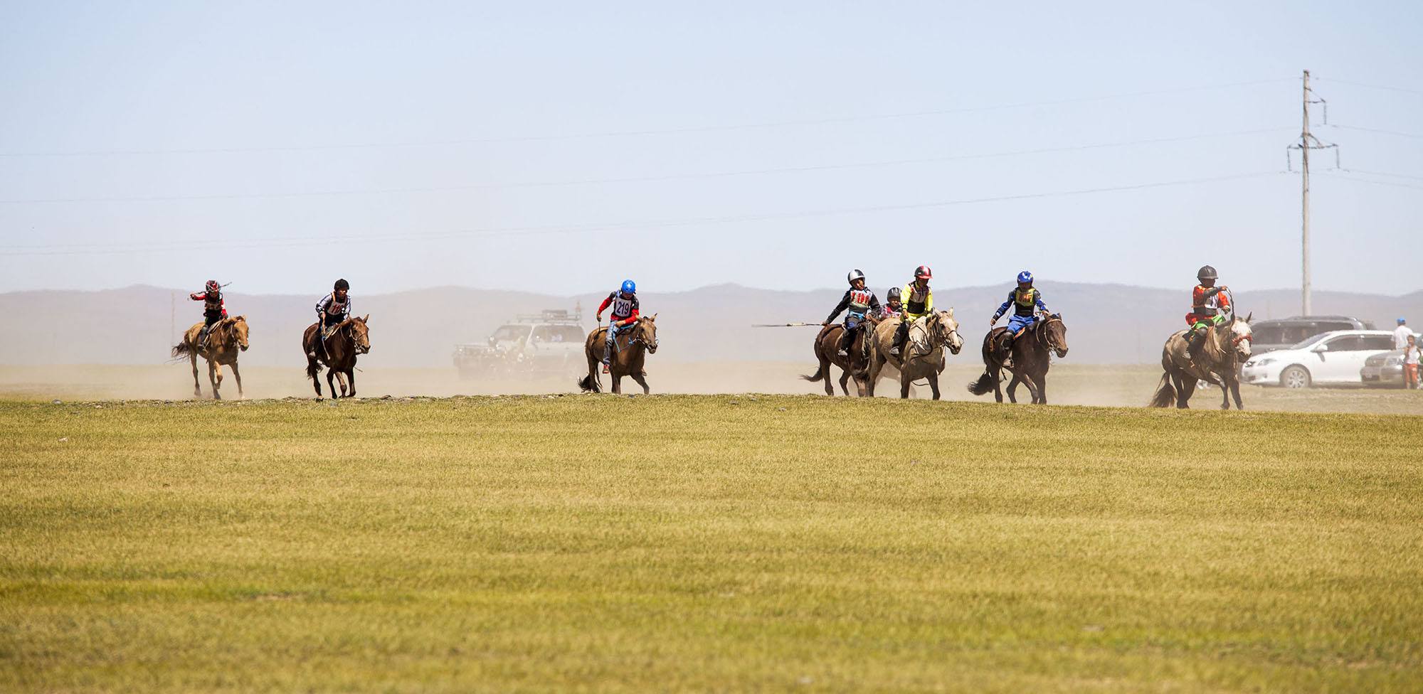 horses and riders racing towards finish line in Naadam