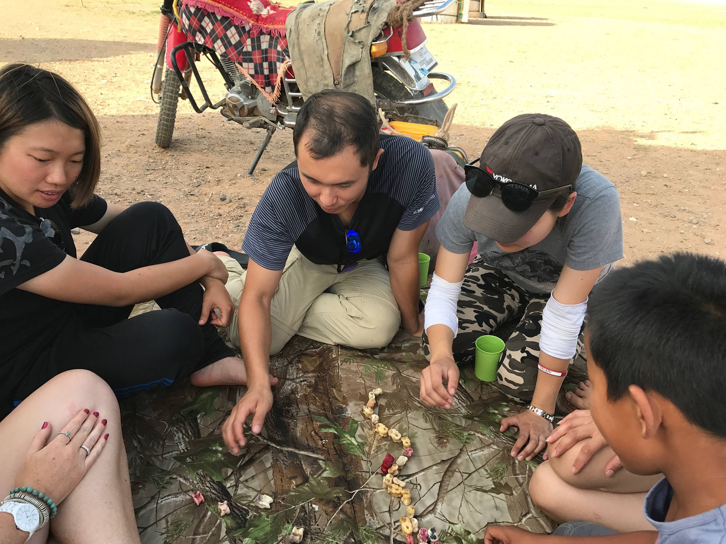 Ariel and Tommy playing game of Shagai at ger camp in Gobi Desert Mongolia