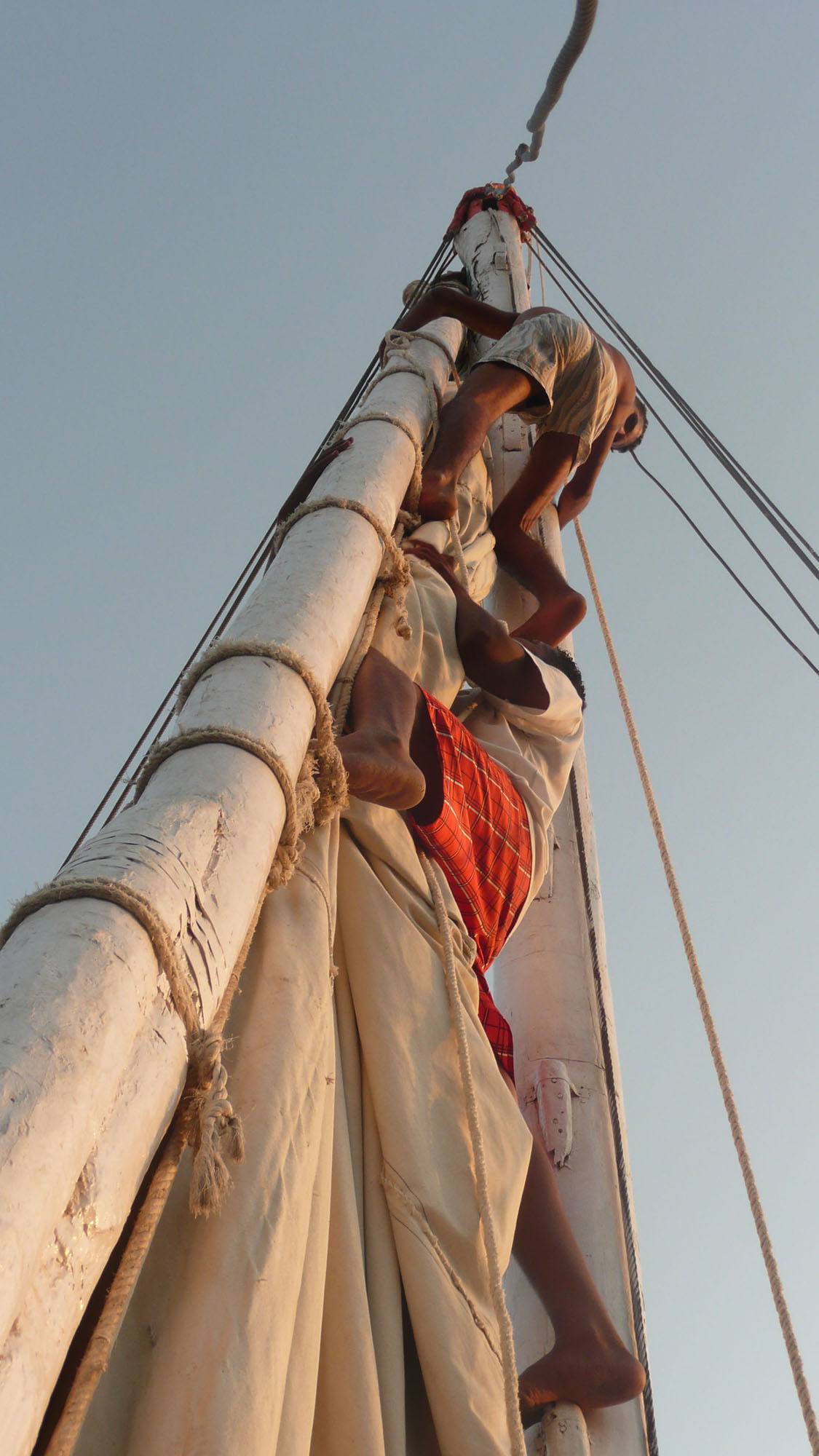 Egyptian men climbing the felucca sail Egypt