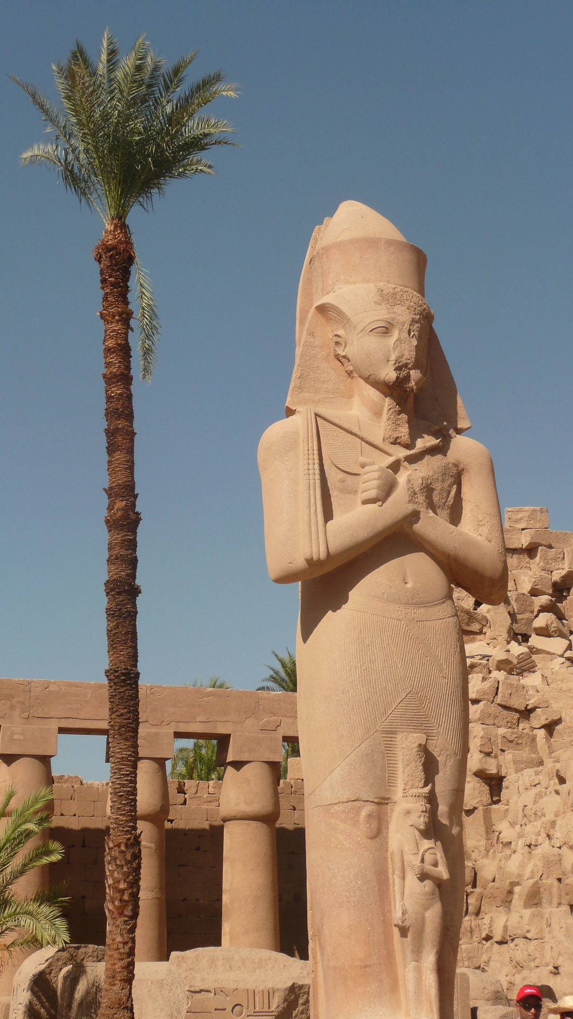 Statue beside palm tree inside Karnak Temple Luxor Egypt