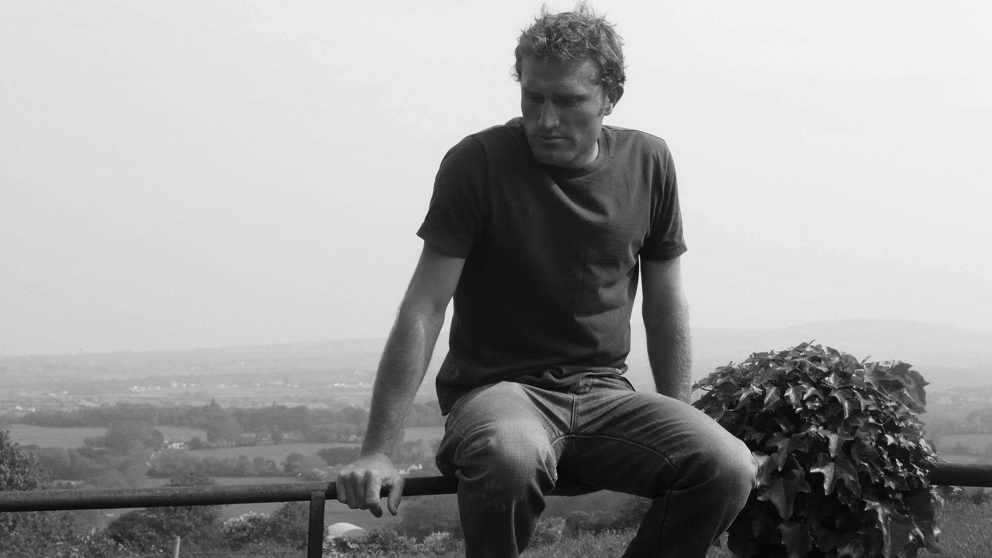 Ben King sitting on a country fence in rural Ireland