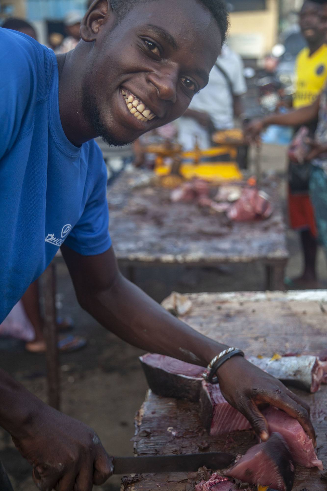 Young Comorian man cutting tuna at market in Mutsamudu Anjouan Comoros