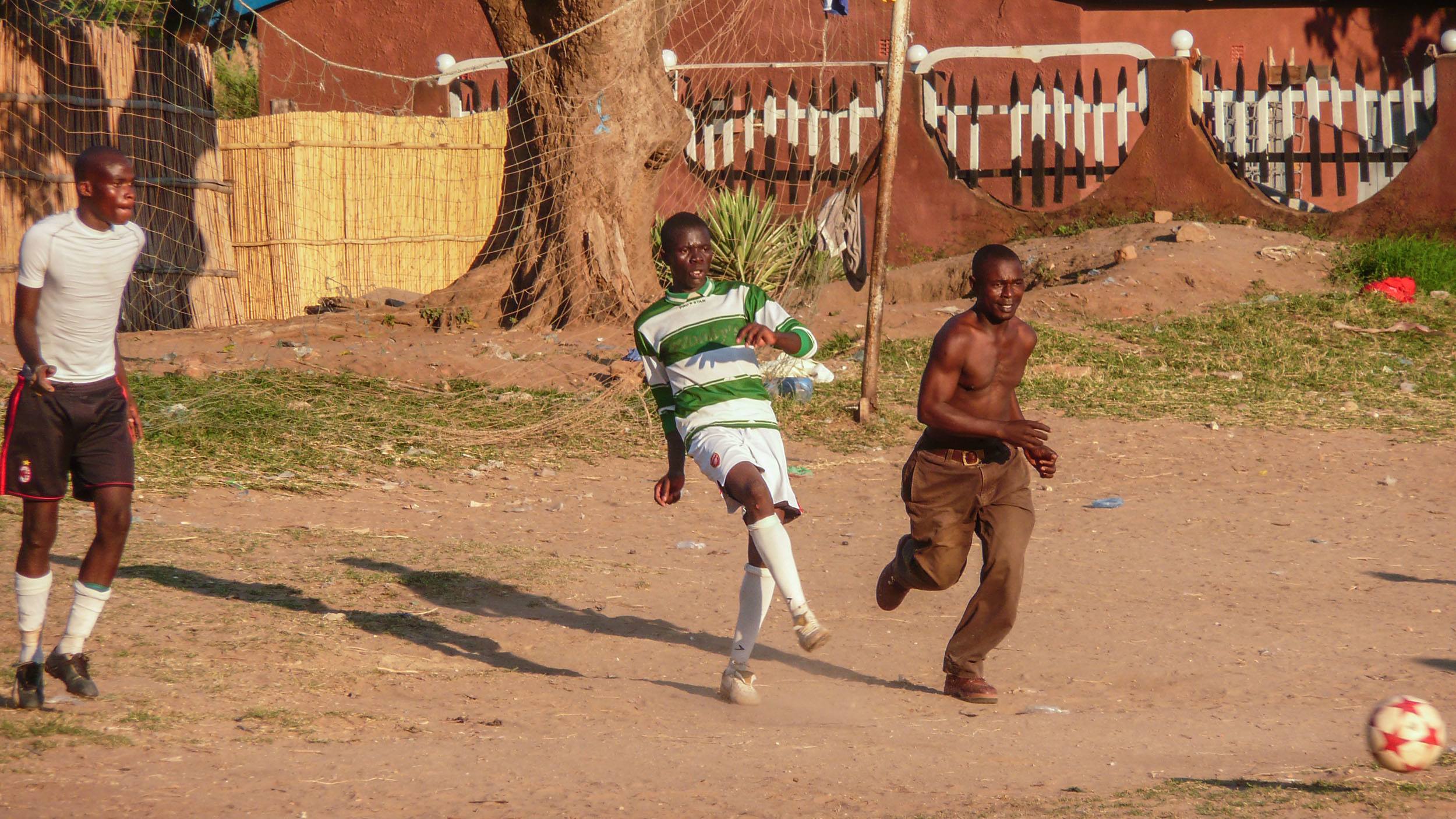 A shirtless man chasing a football in Nkhata Bay Malawi