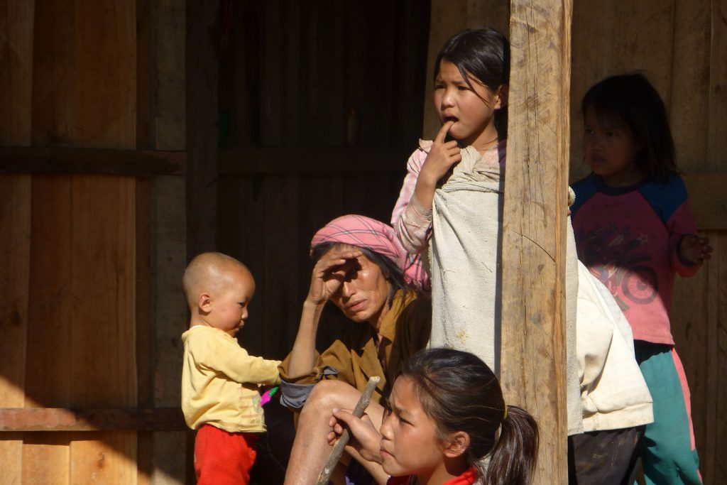 Akha mother and children sitting on deck of house in village of Laos
