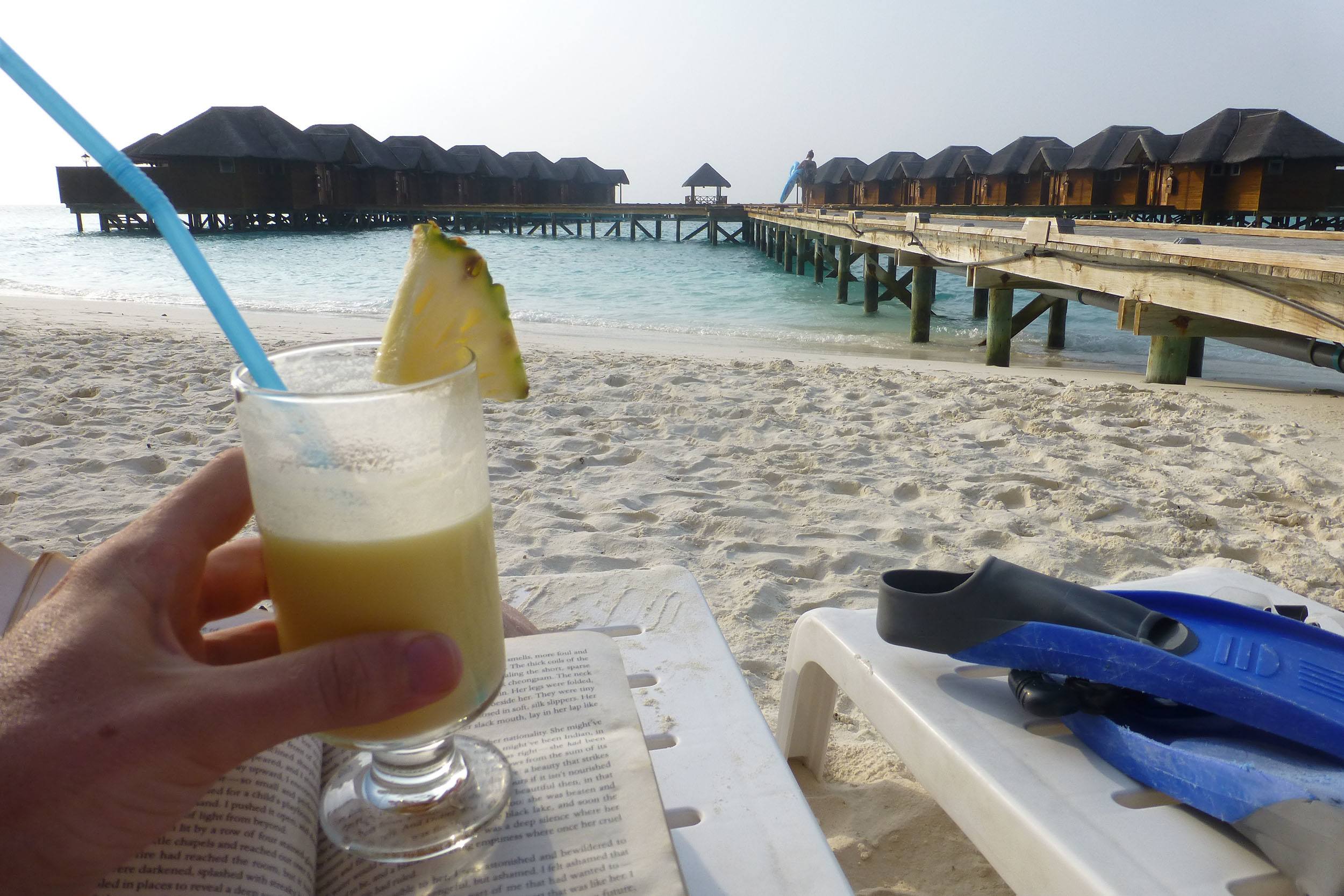 Ben enjoying a cocktail in front of overwater bungalows on Fihalhohi the Maldives