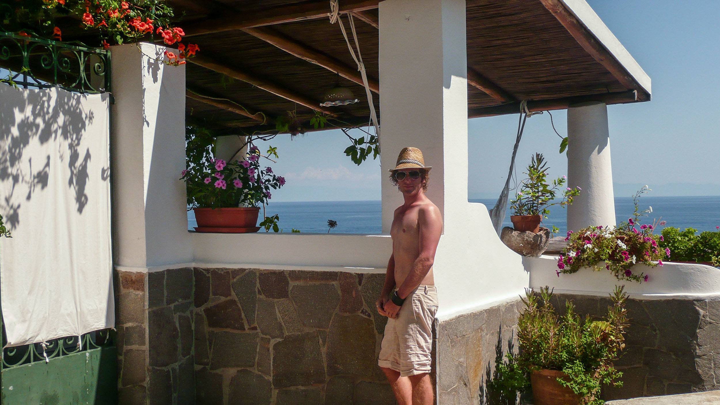 Ben leaning against white house on Panarea in Sicily Italy