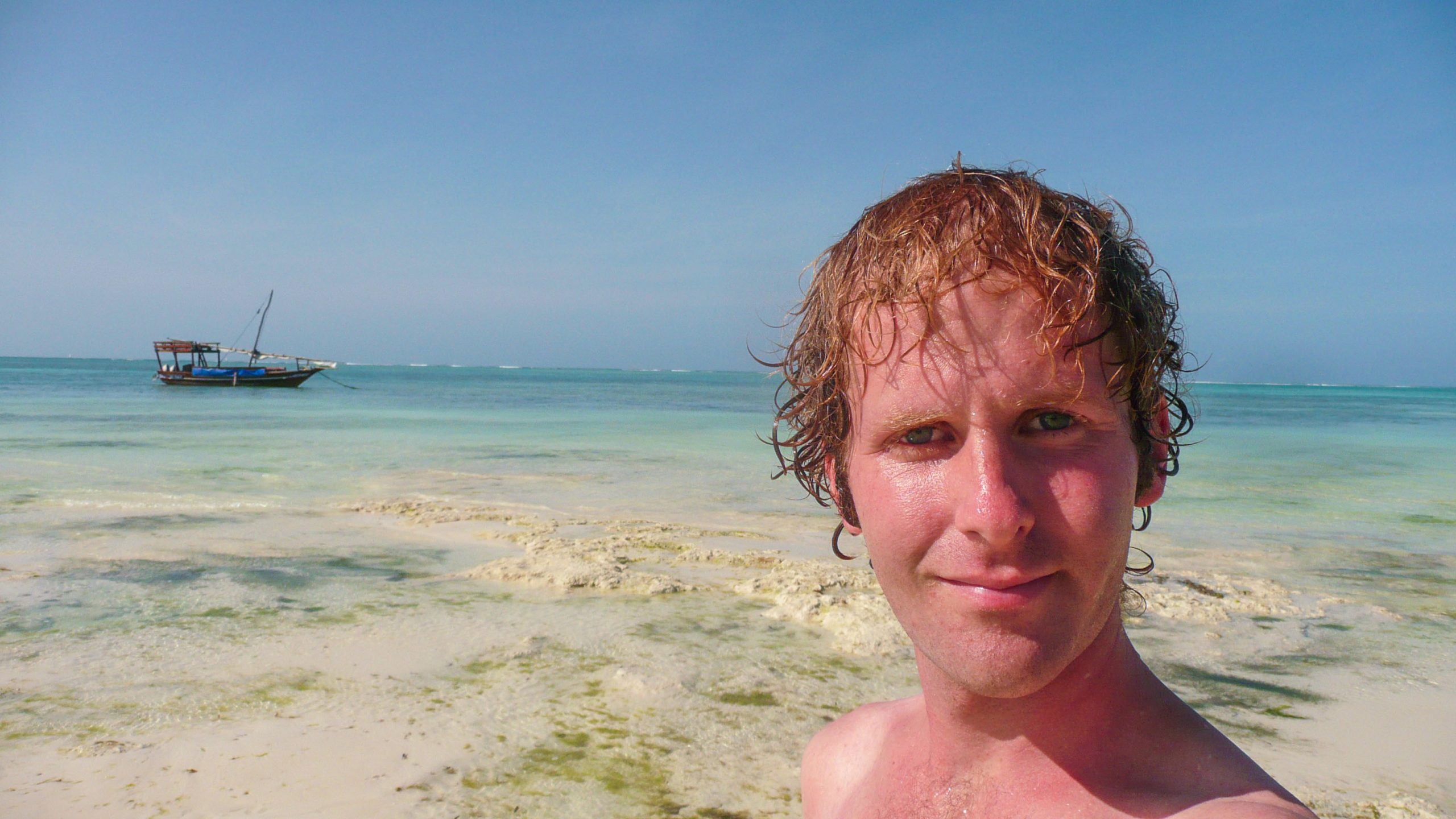 Ben on beach of Zanzibar with boat in background Tanzania