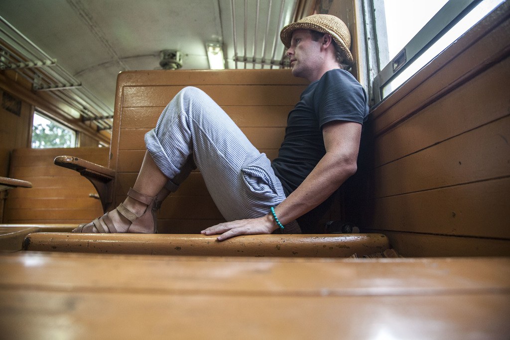 Ben on wooden seat of train heading to Kanchanaburi Thailand