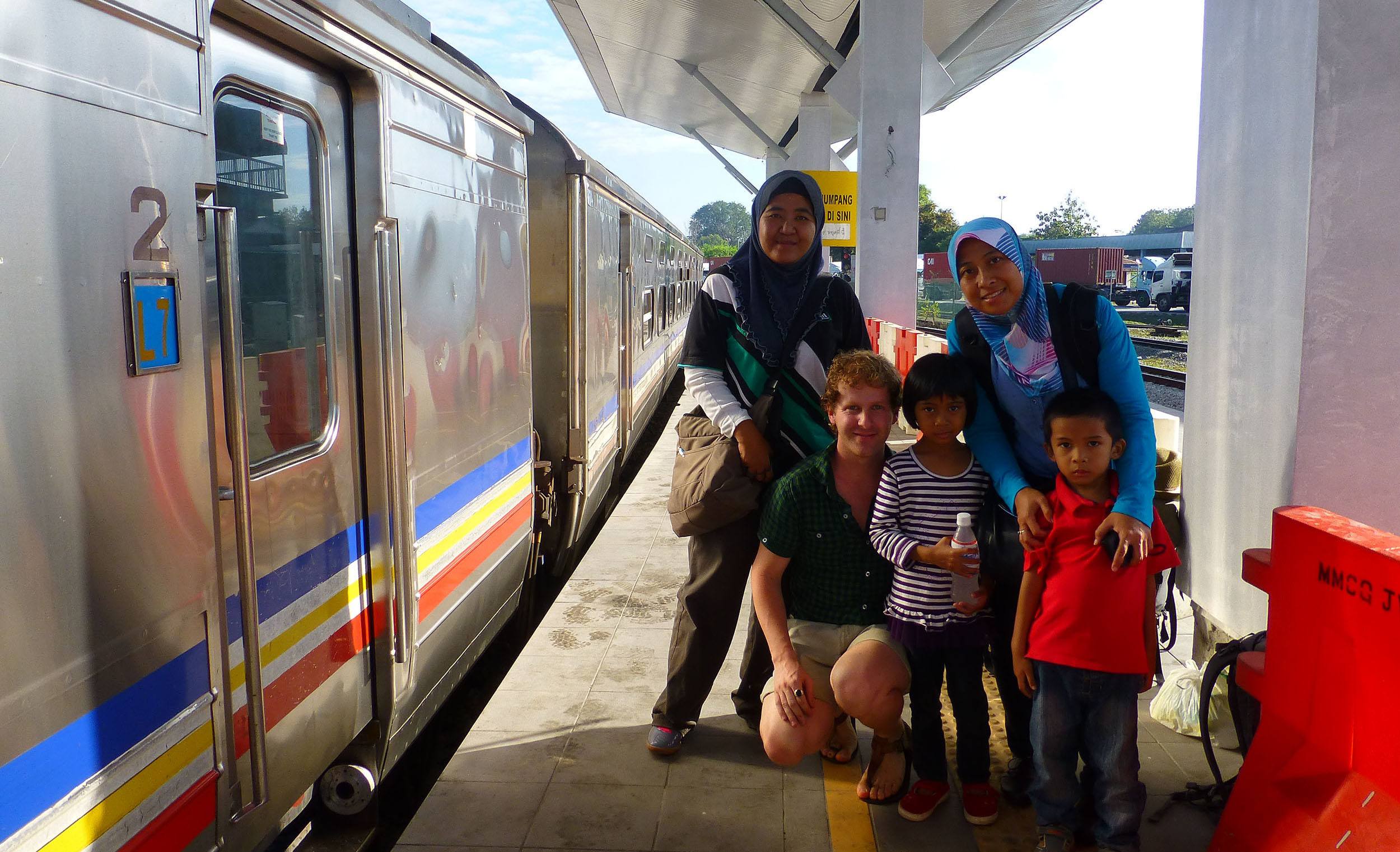 Ben posing with a Malaysian family at a train station in Malaysia en route to Thailand
