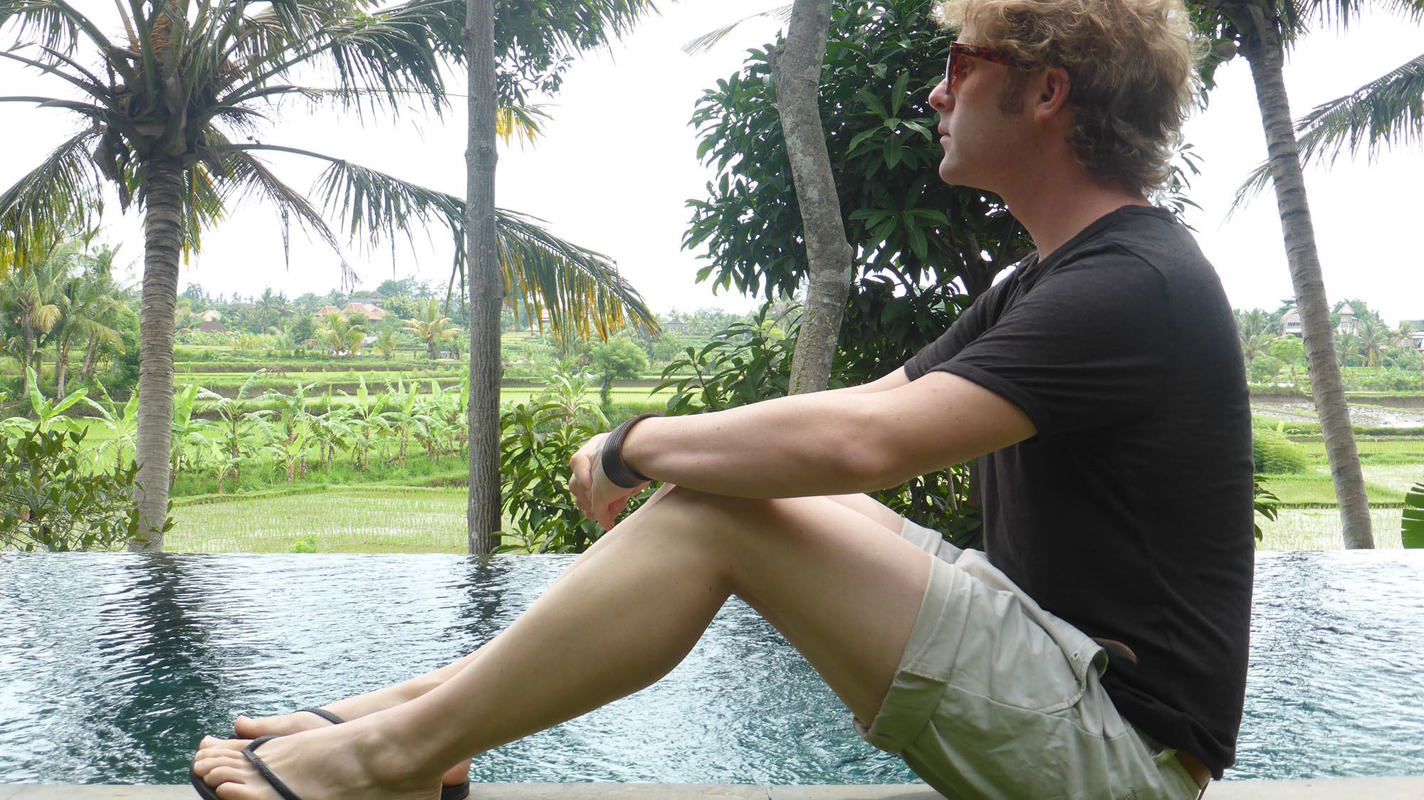 Ben sitting beside lap pool at Ubud Padi Villas in Bali Indonesia