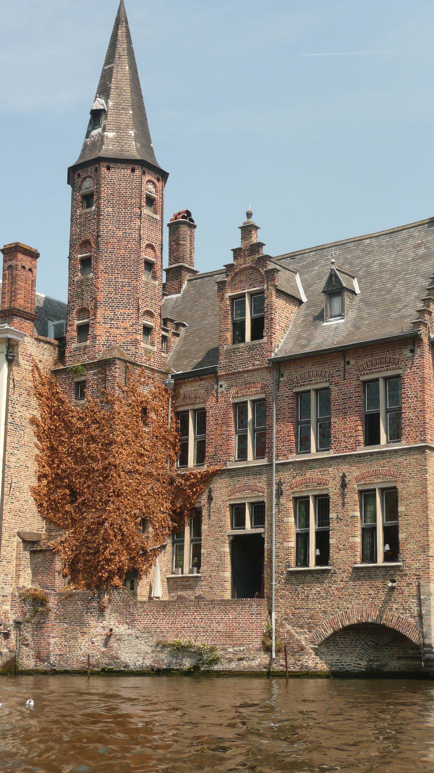 Building with a spire on canal cruise in Bruge Belgium