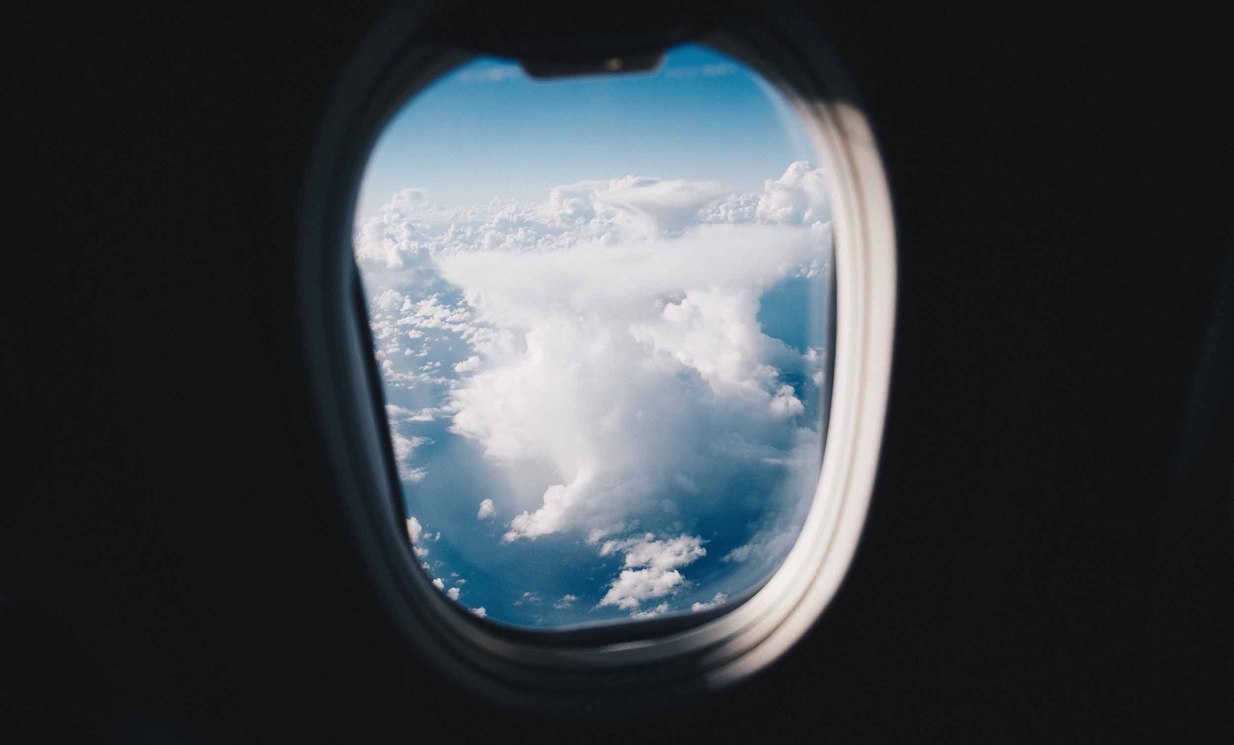 Clouds and blue sky outside a plane window