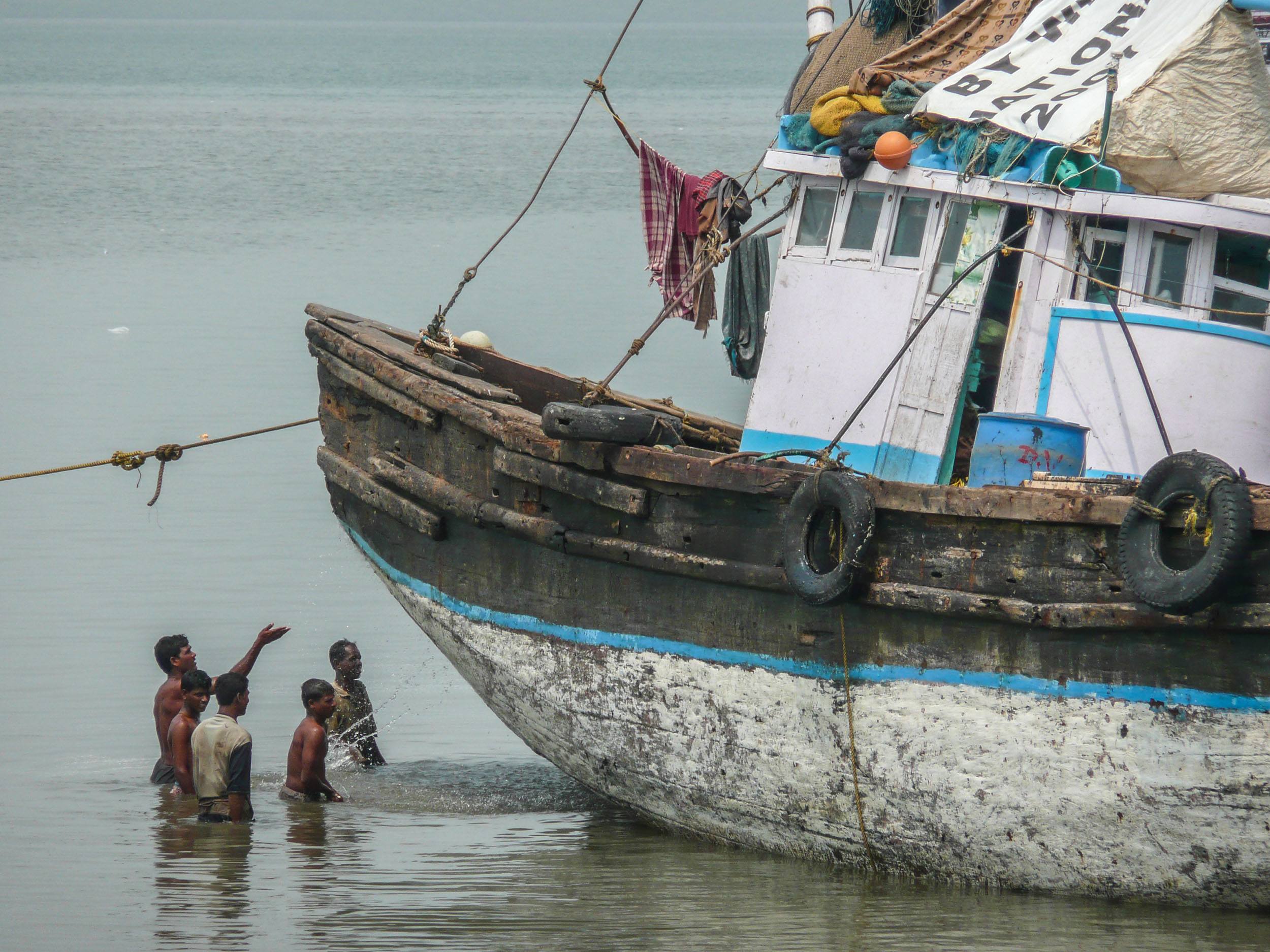 Indian men in water near Elephanta island washing a boat Mumbai India