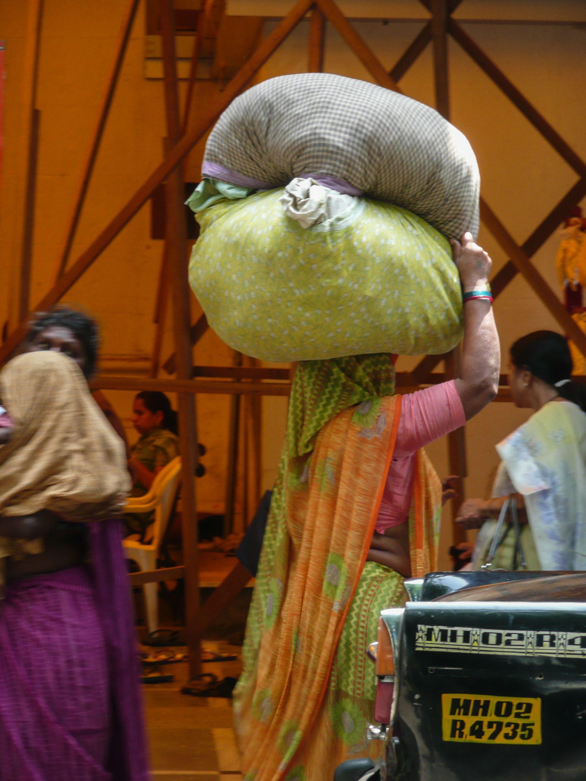 Indian woman in sari carrying bags on her head in Mumbai India