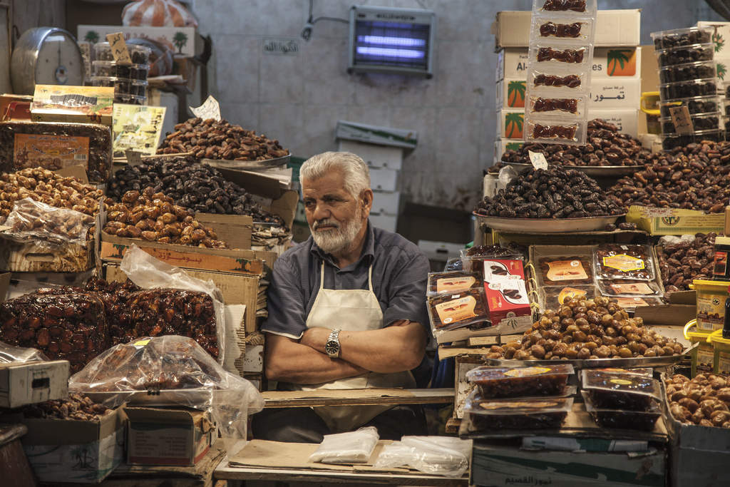 Man sitting at date and prune stall inside Souq Al-Mubarakiya Kuwait