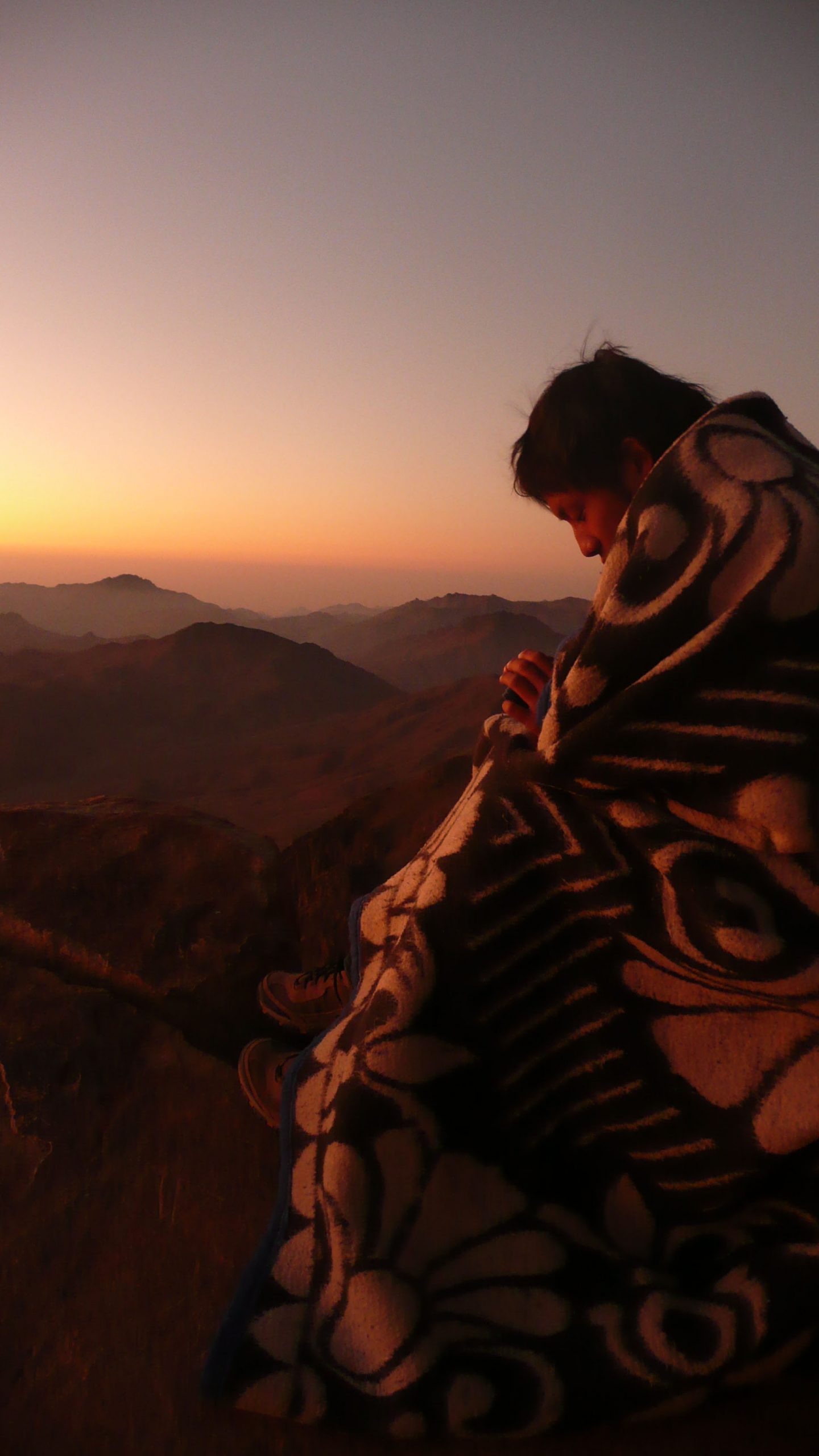 Man wrapped in blanket waiting for sunrise on Mt Sinai Egypt