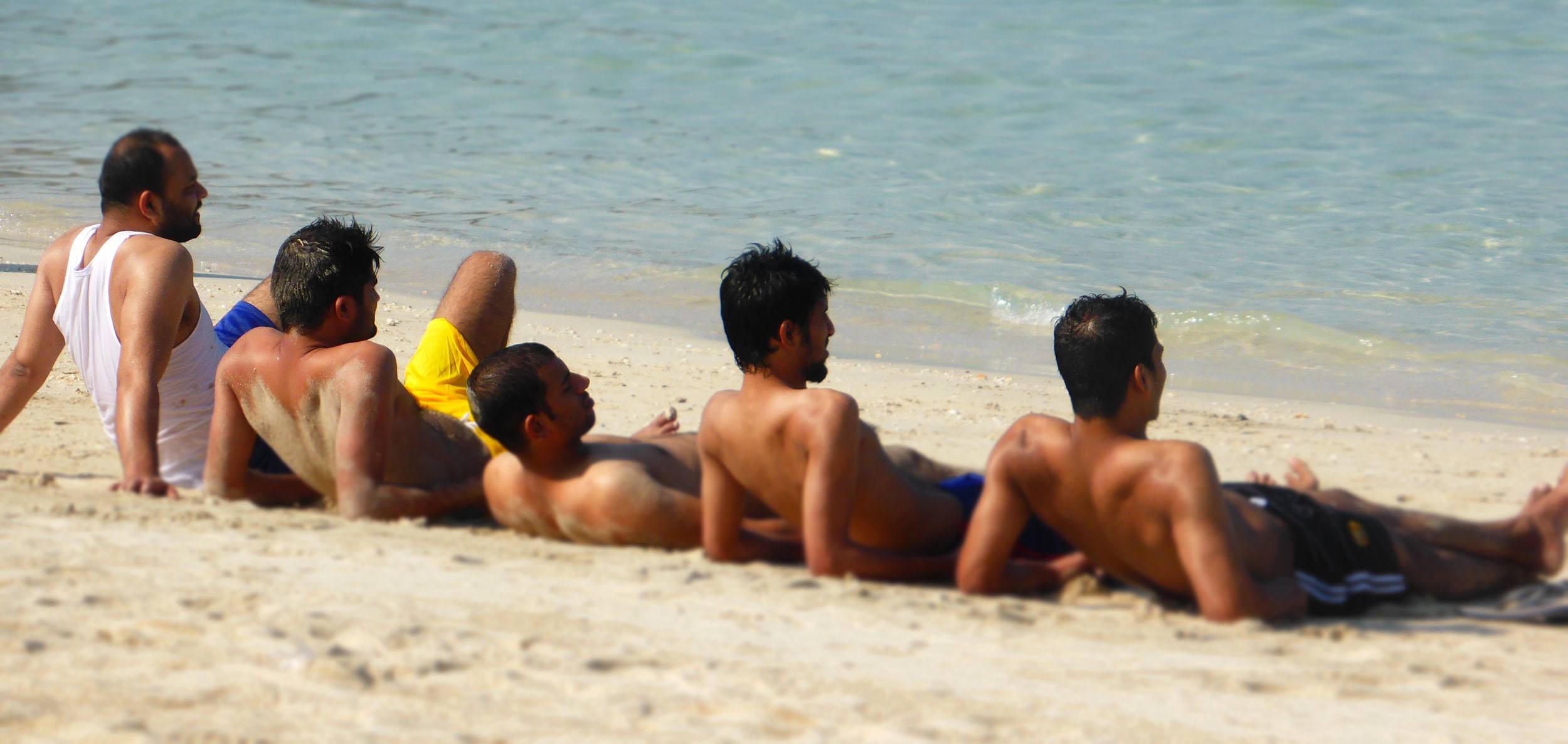 Men laying in Jumeirah Beach in Dubai