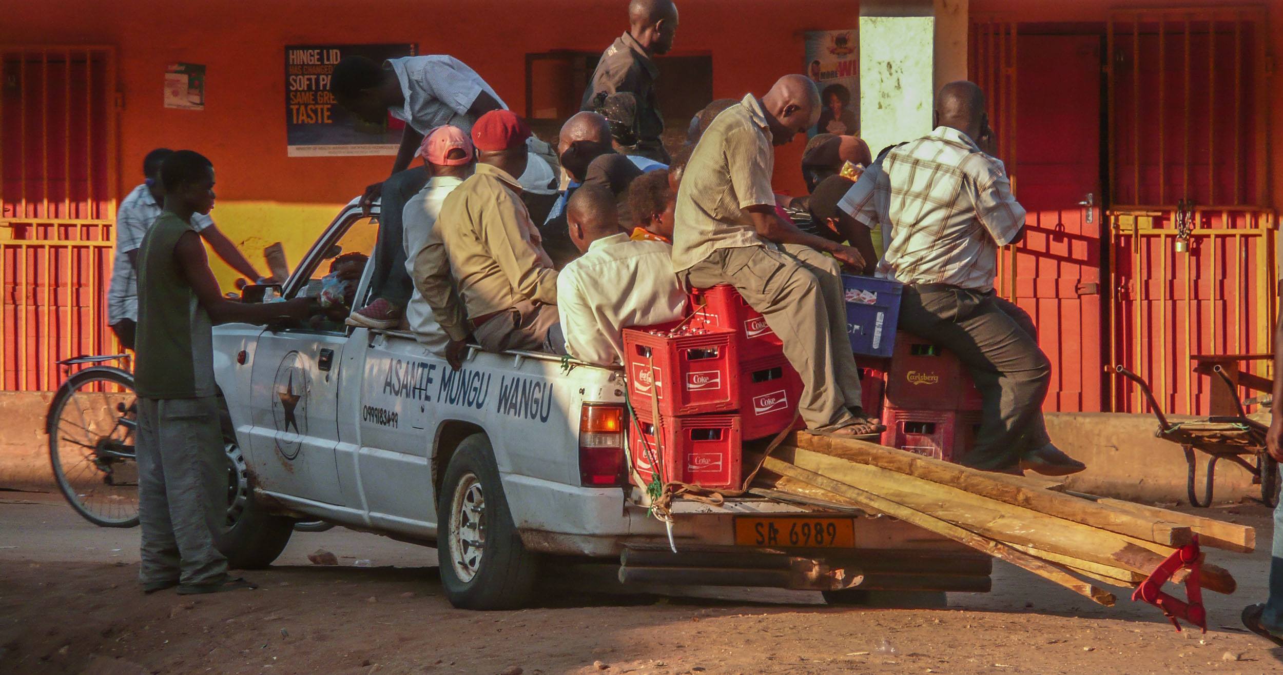 Men sitting in overfilled tray of ute in Nkhata Bay Malawi