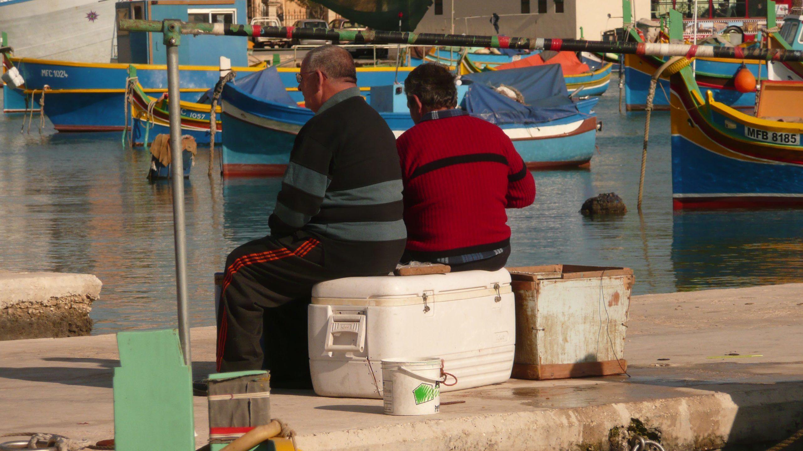 Men sitting on esky near water in Marsaxlokk Malta