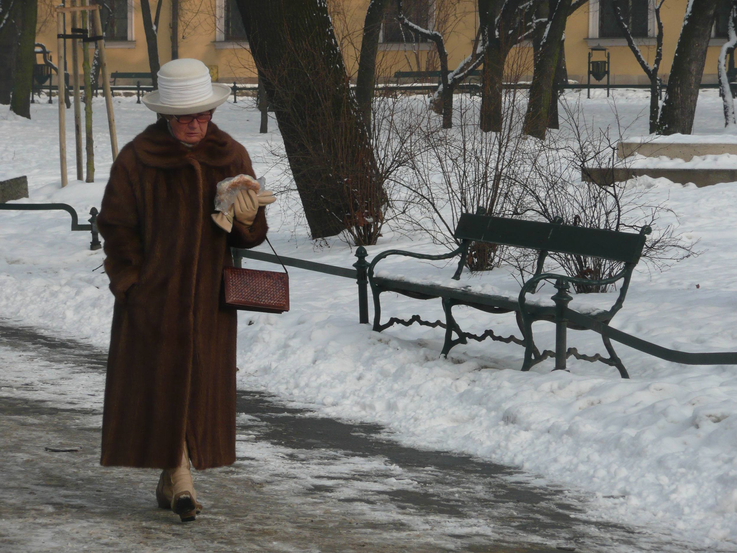 Polish woman dressed in a fur coat walking through a park in Krakow Poland