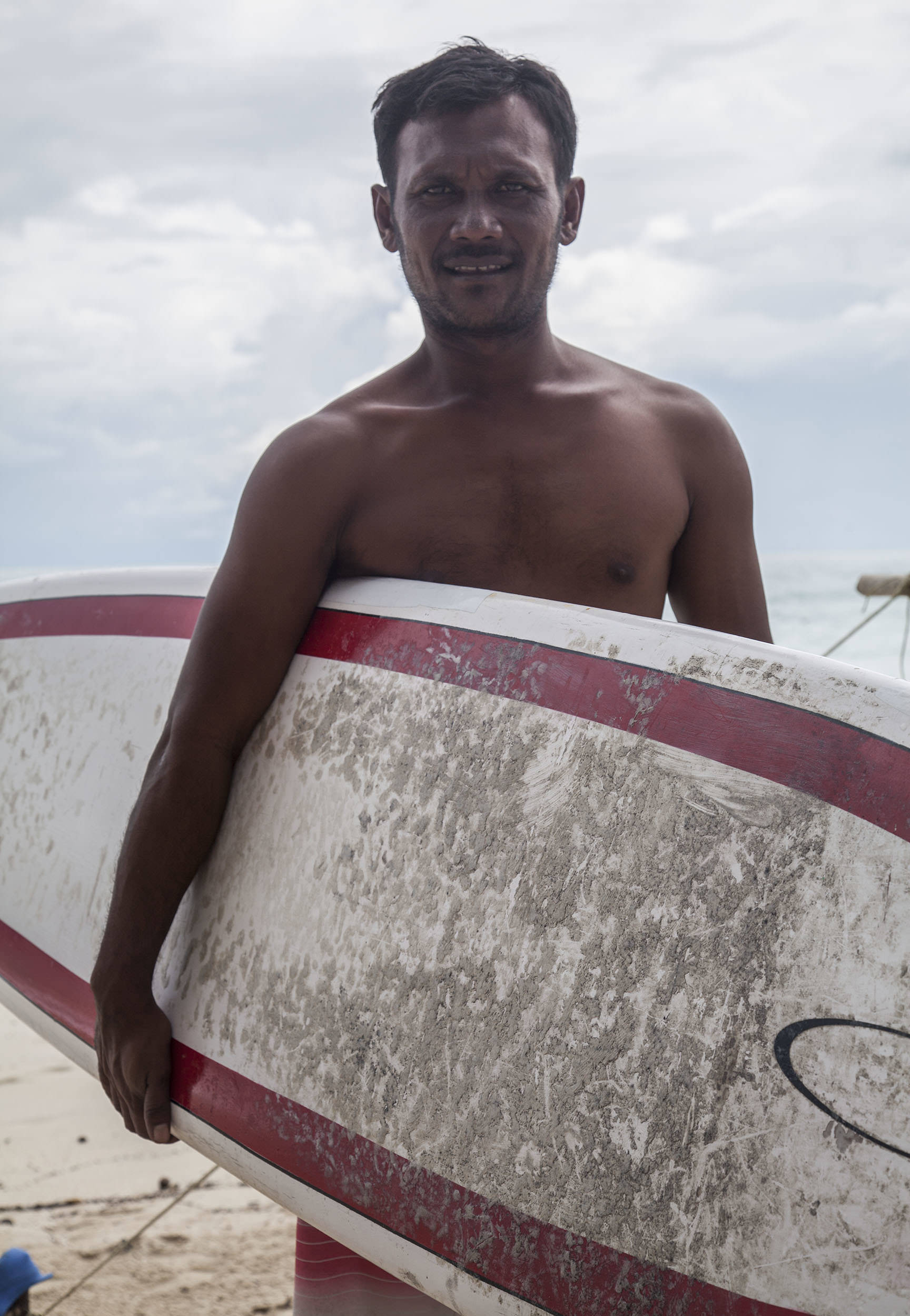 Thai man with surfboard under his arm on Chaweng Beach Koh Samui Thailand