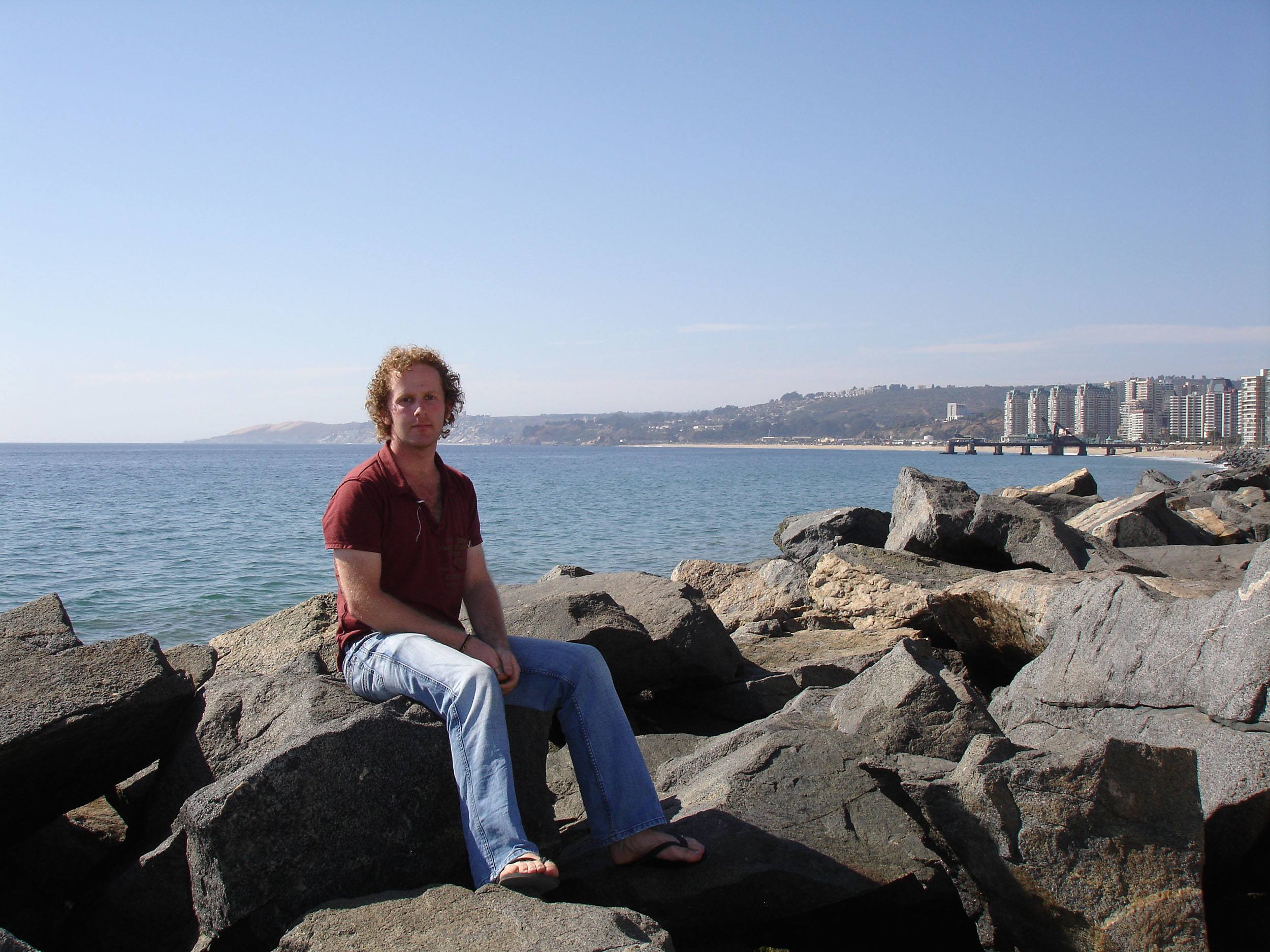 Ben sitting on rocks beside beach in Viña del Mar Chile