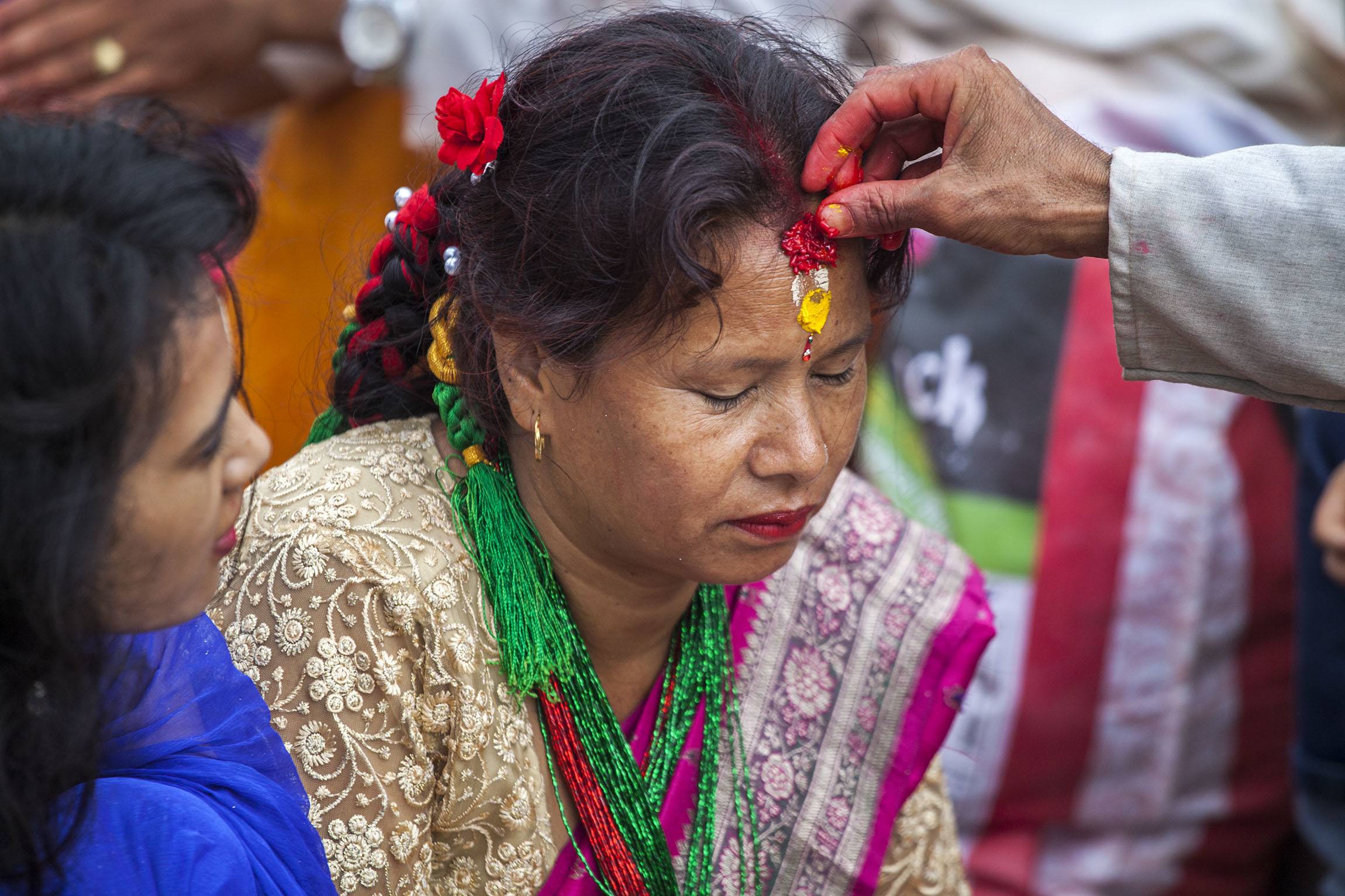 Bindi being applied to forehead of woman during Teej celebrations in Kathmandu Nepal