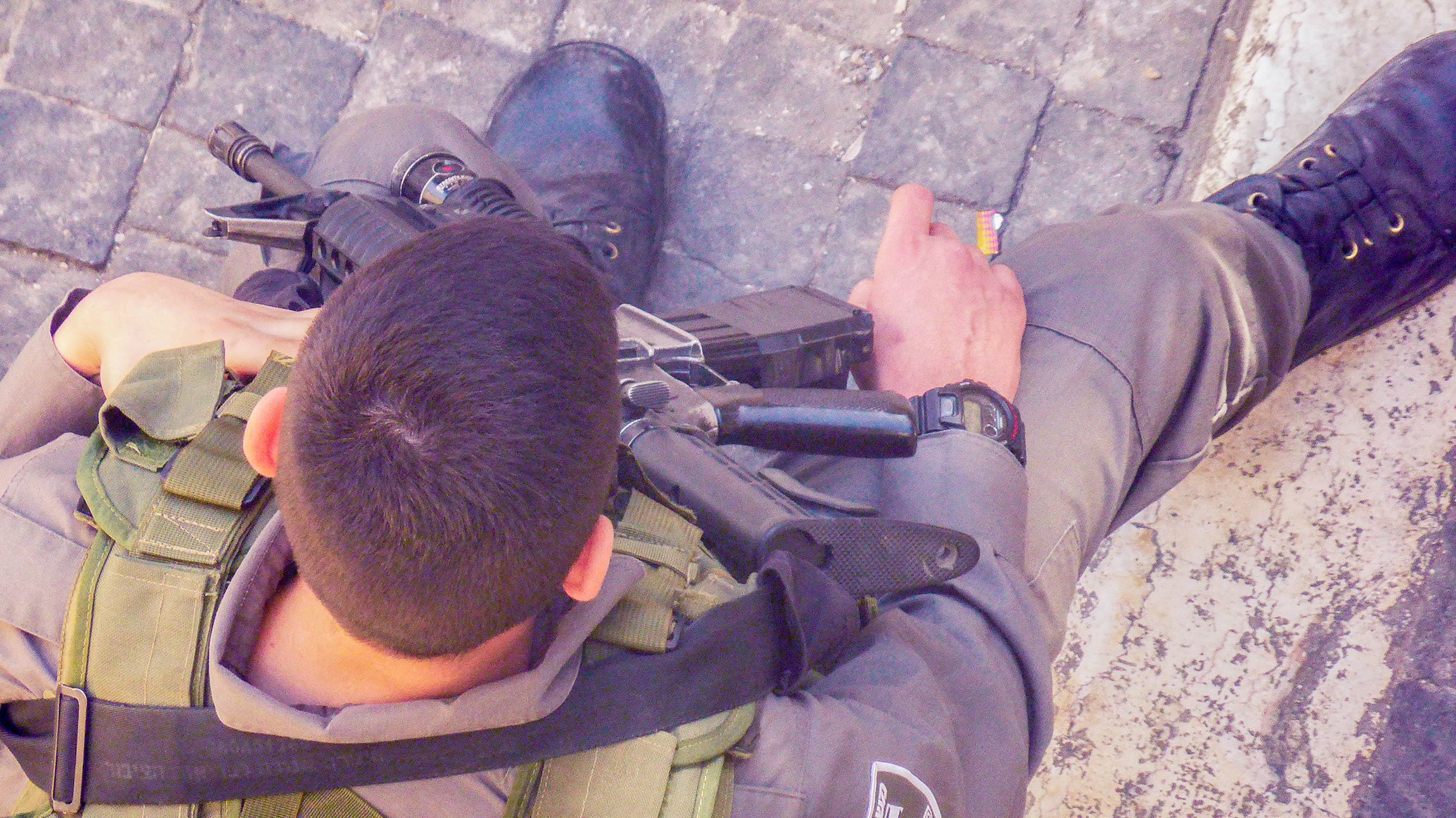 Man wielding M16 rifle sitting in the streets of Jerusalem Israel