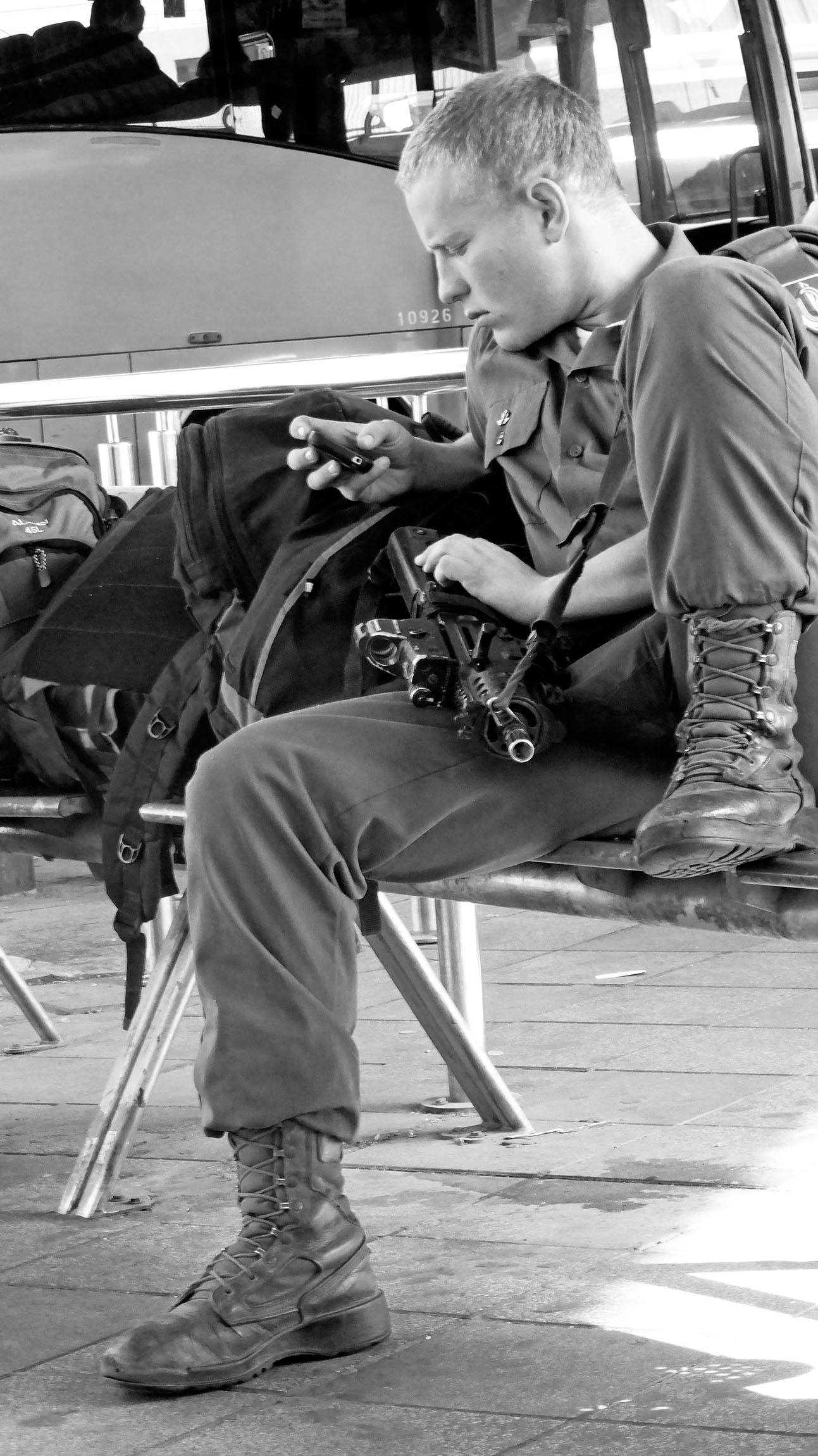 Soldier wielding rifle while waiting for a bus in Haifa Israel