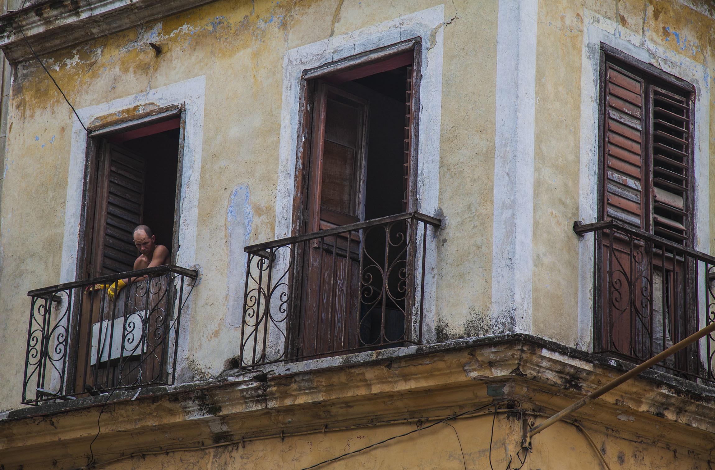 A Cuban man standing on his balcony in a building in Havana Cuba