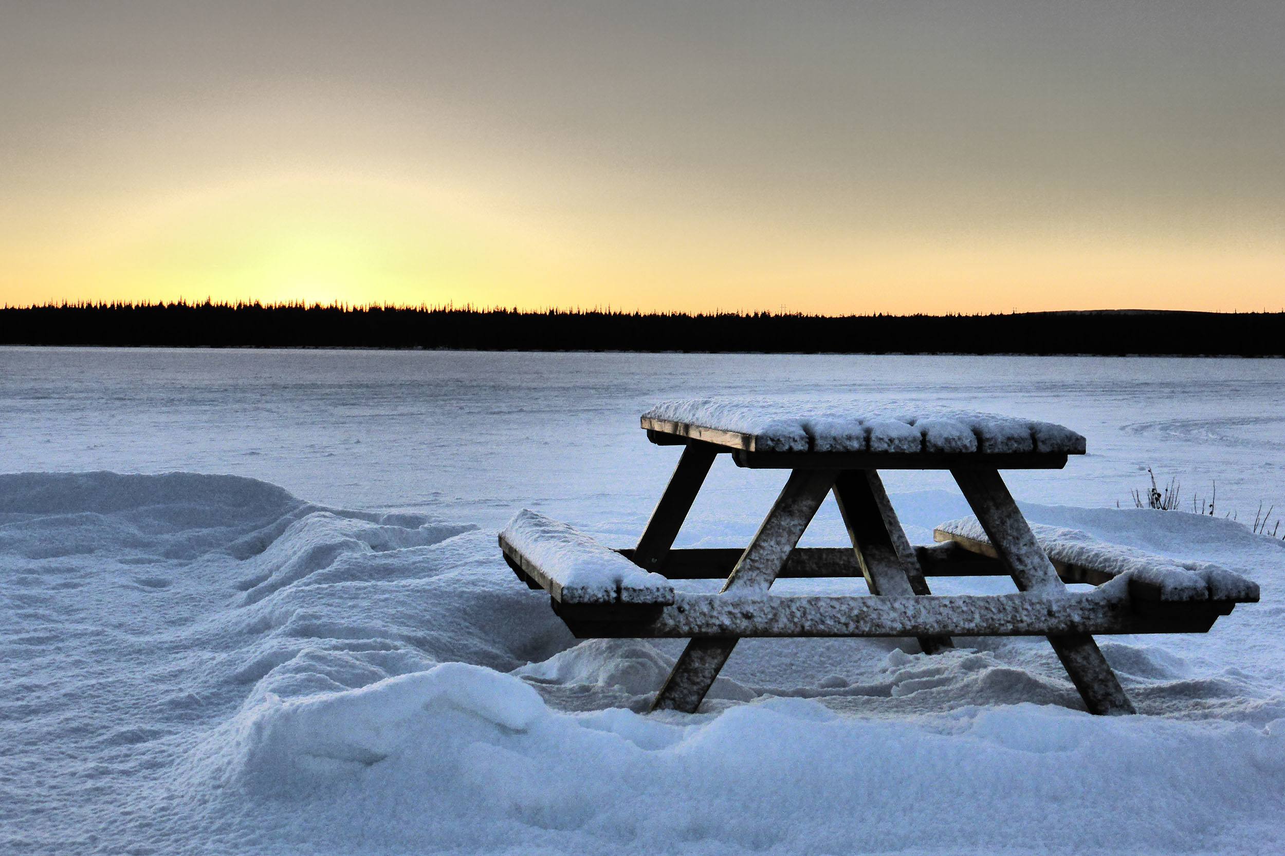 A bench beside a frozen lake at Camp Alta Kiruna Sweden