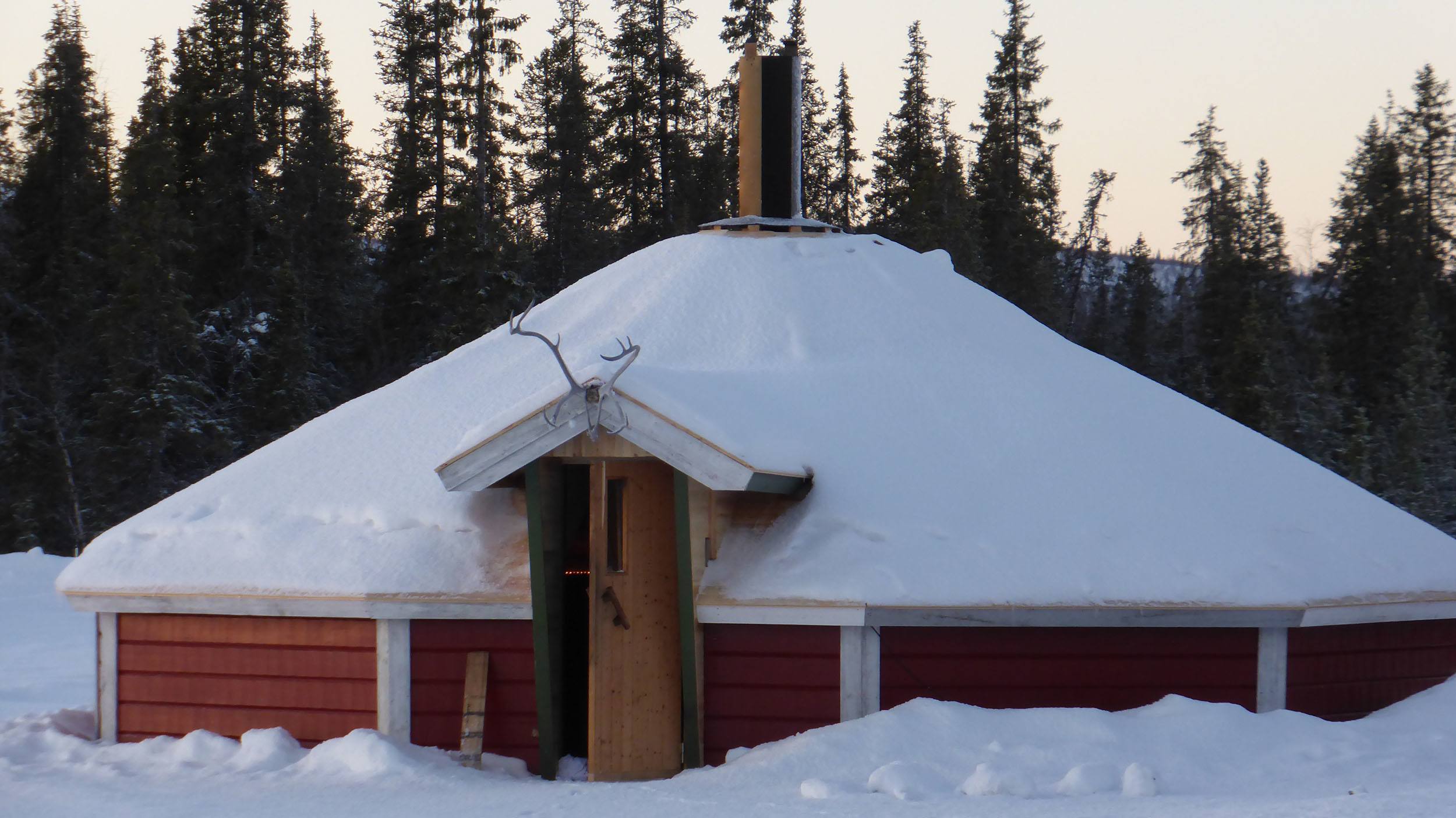 A large communal cabin at Camp Alta Sweden containing a fire and chimney