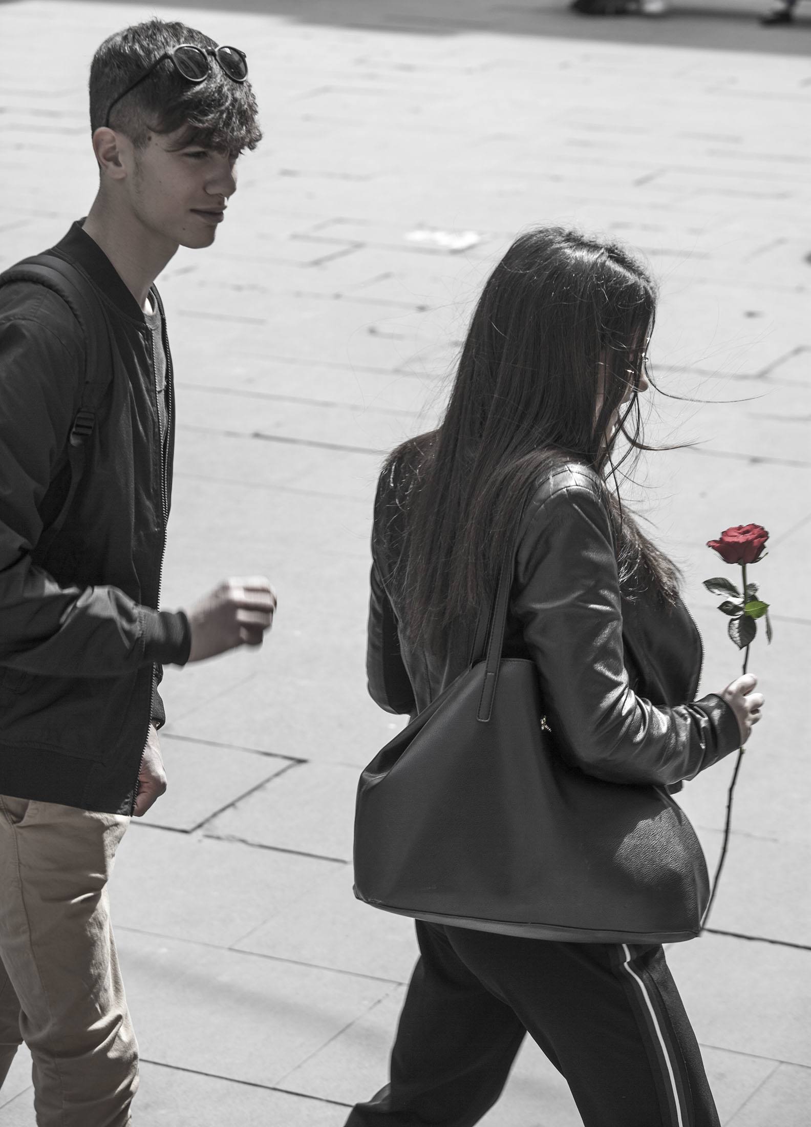 A man and a woman with a red rose walking through the streets of Rome Italy