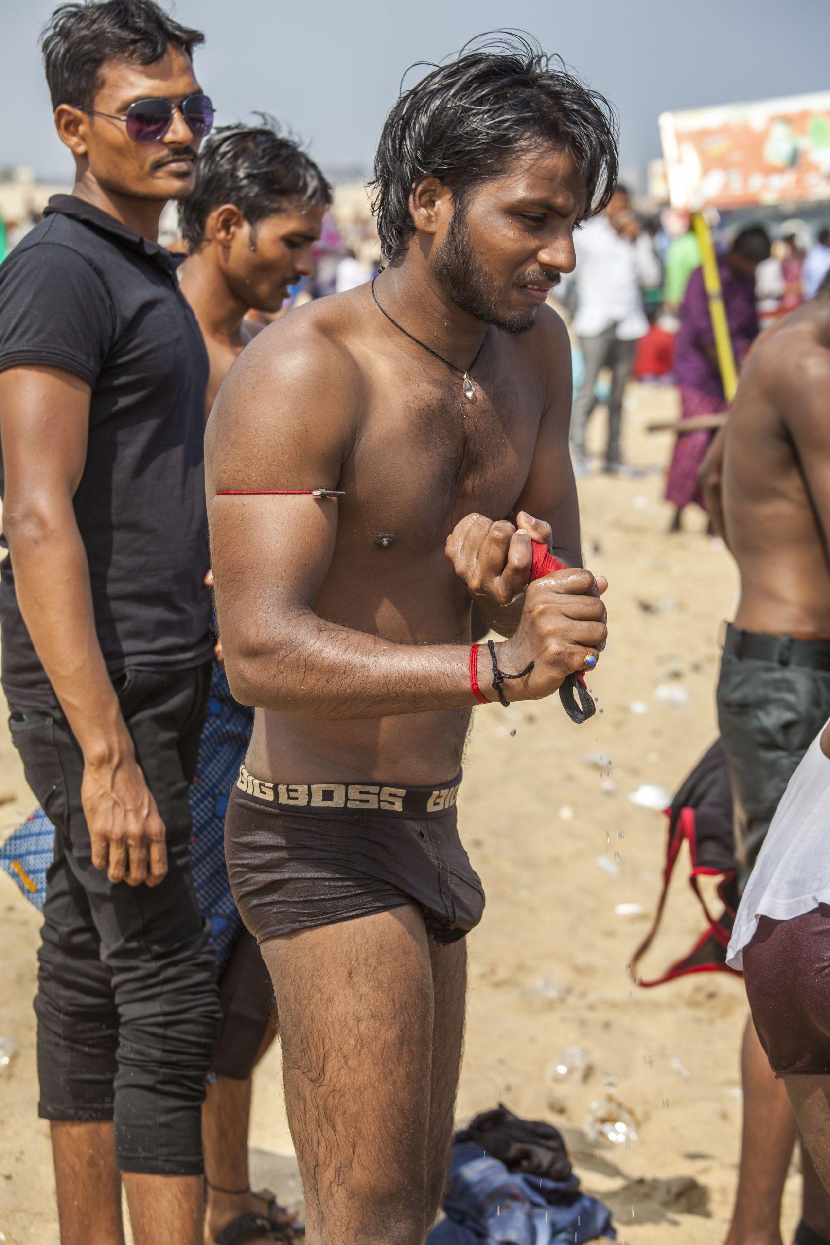 A man in underwear getting changed on the beach in Chennai India