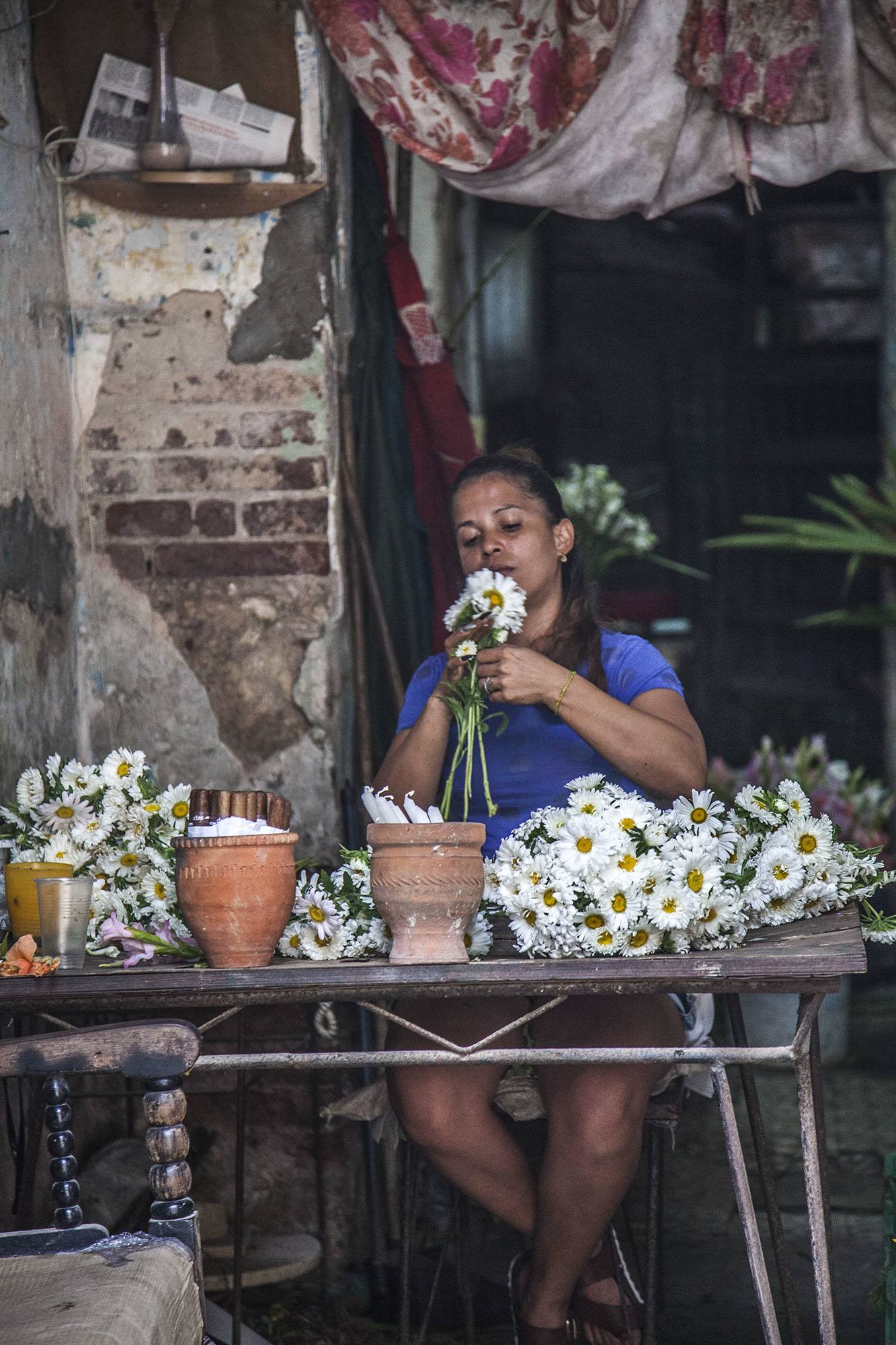 A woman arranging flowers in a crumbling shop in Havana Cuba