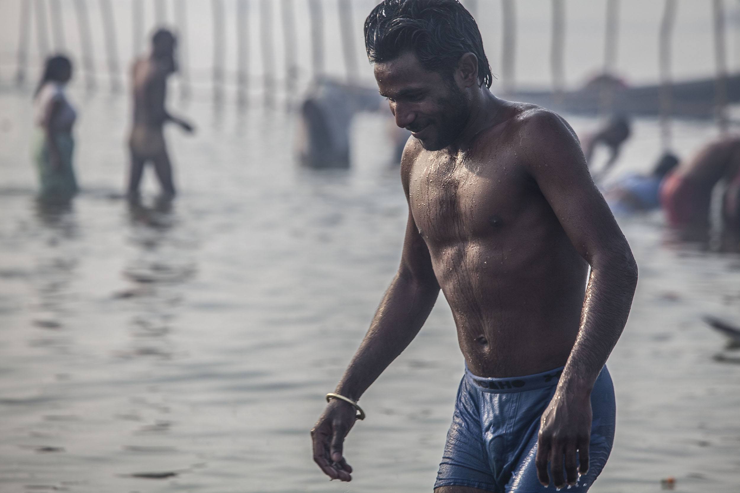 An Indian man in wet underwear emerging from the Ganges at Marg Melah in Allahabad India