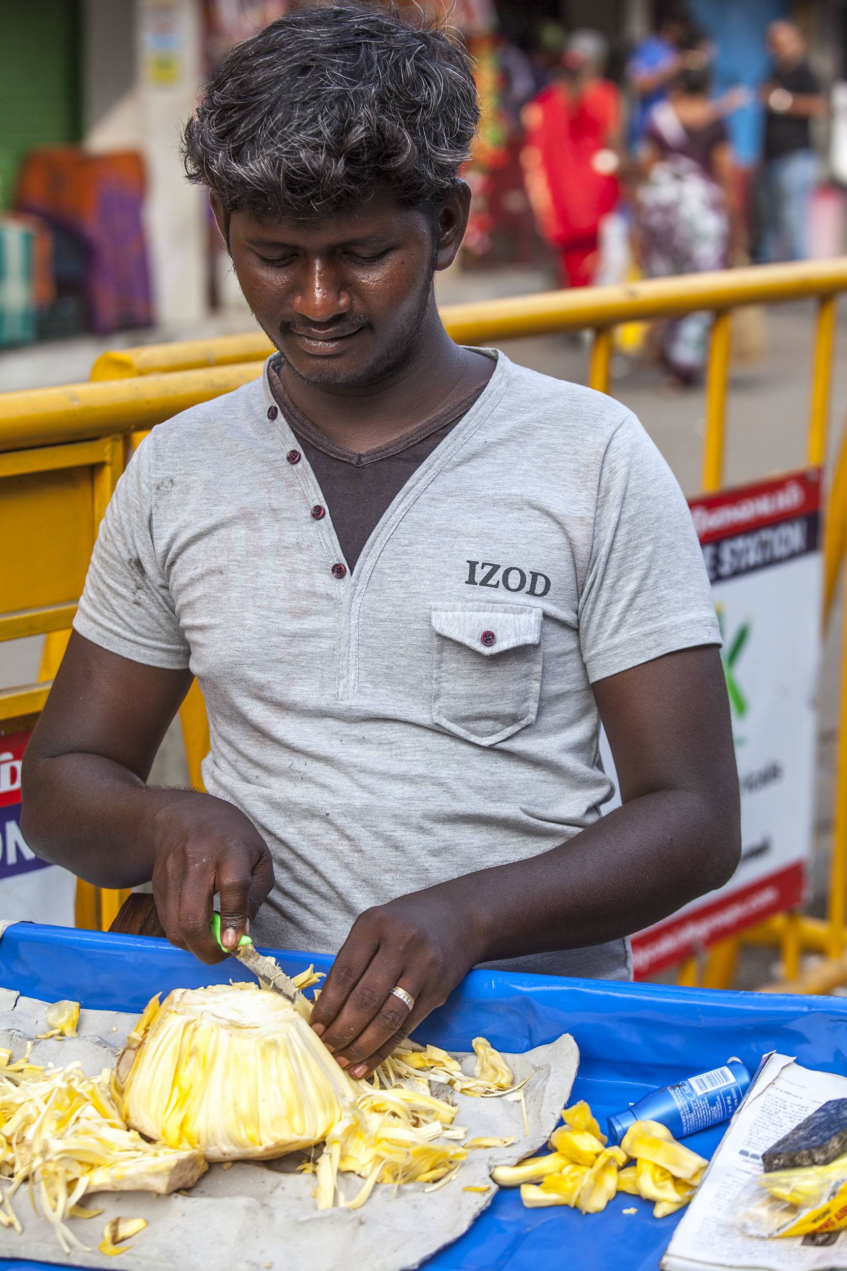 An Indian man slicing fruit by the beach in Chennai India