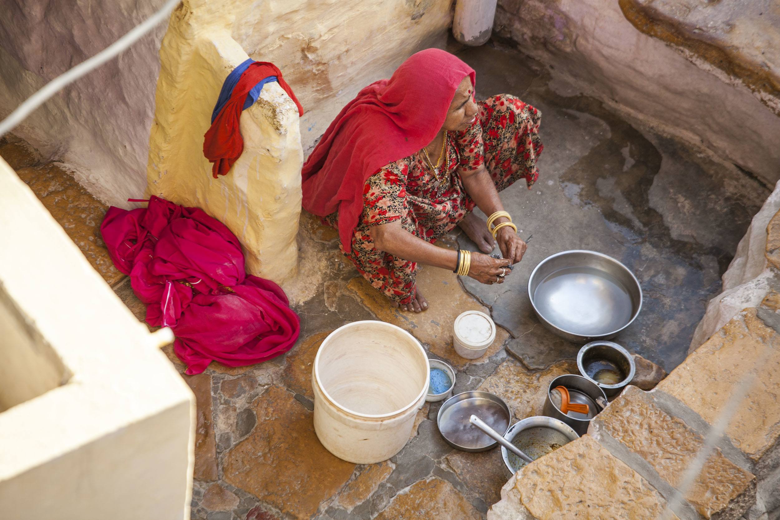 An Indian woman washing dishes on the street in Jaisalmer India