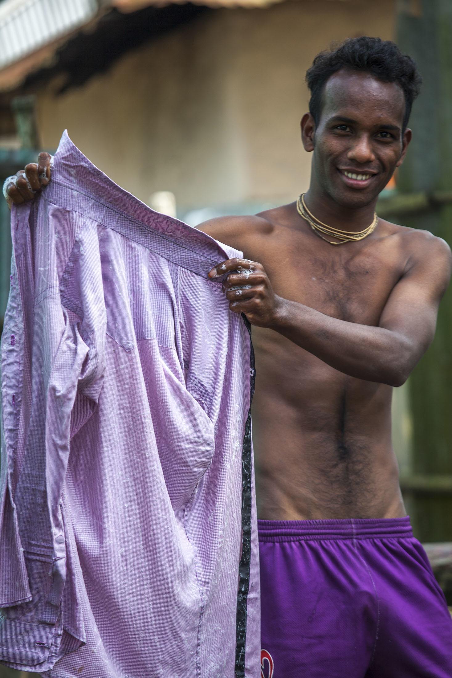 Bangladeshi man smiling shirtless holding purple shirt Srimangal Bangladesh