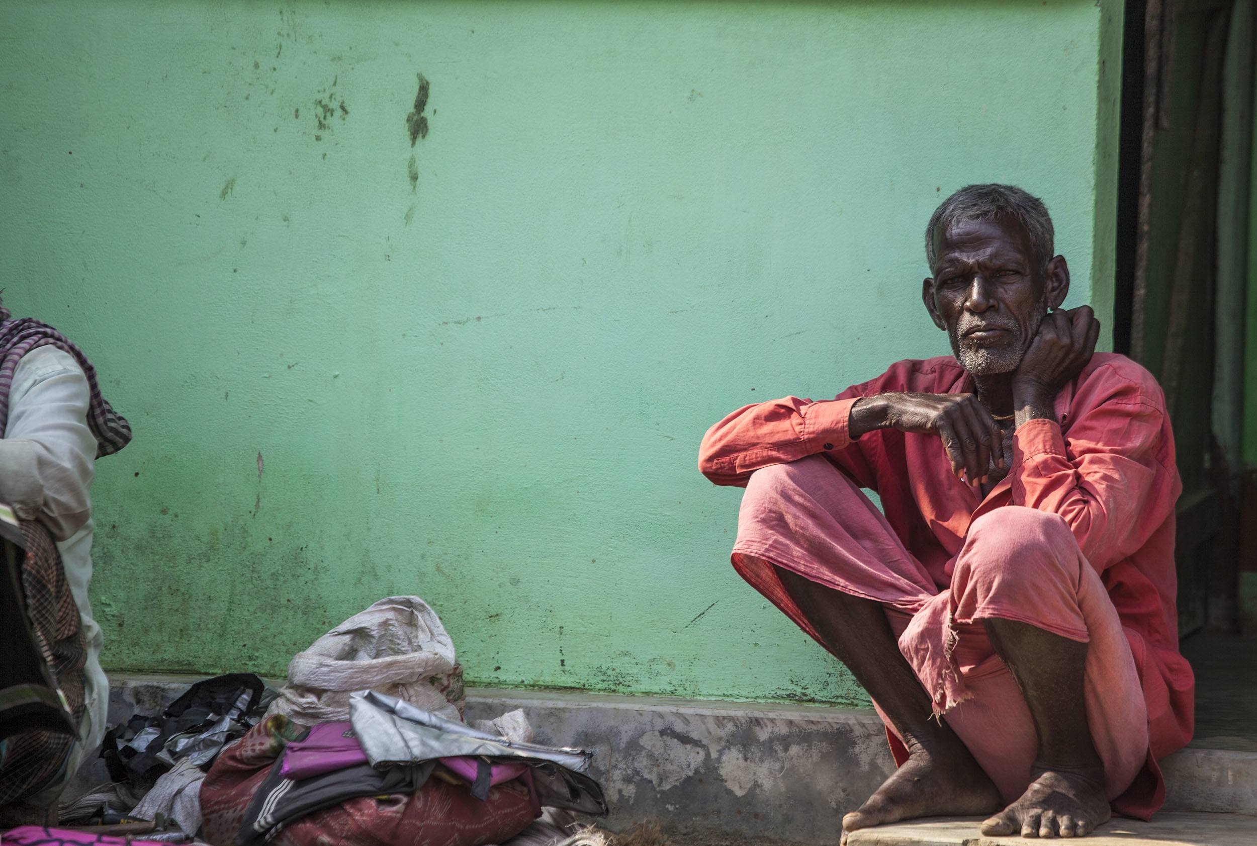 Bangladeshi man squatting beside green wall Srimangal Bangladesh