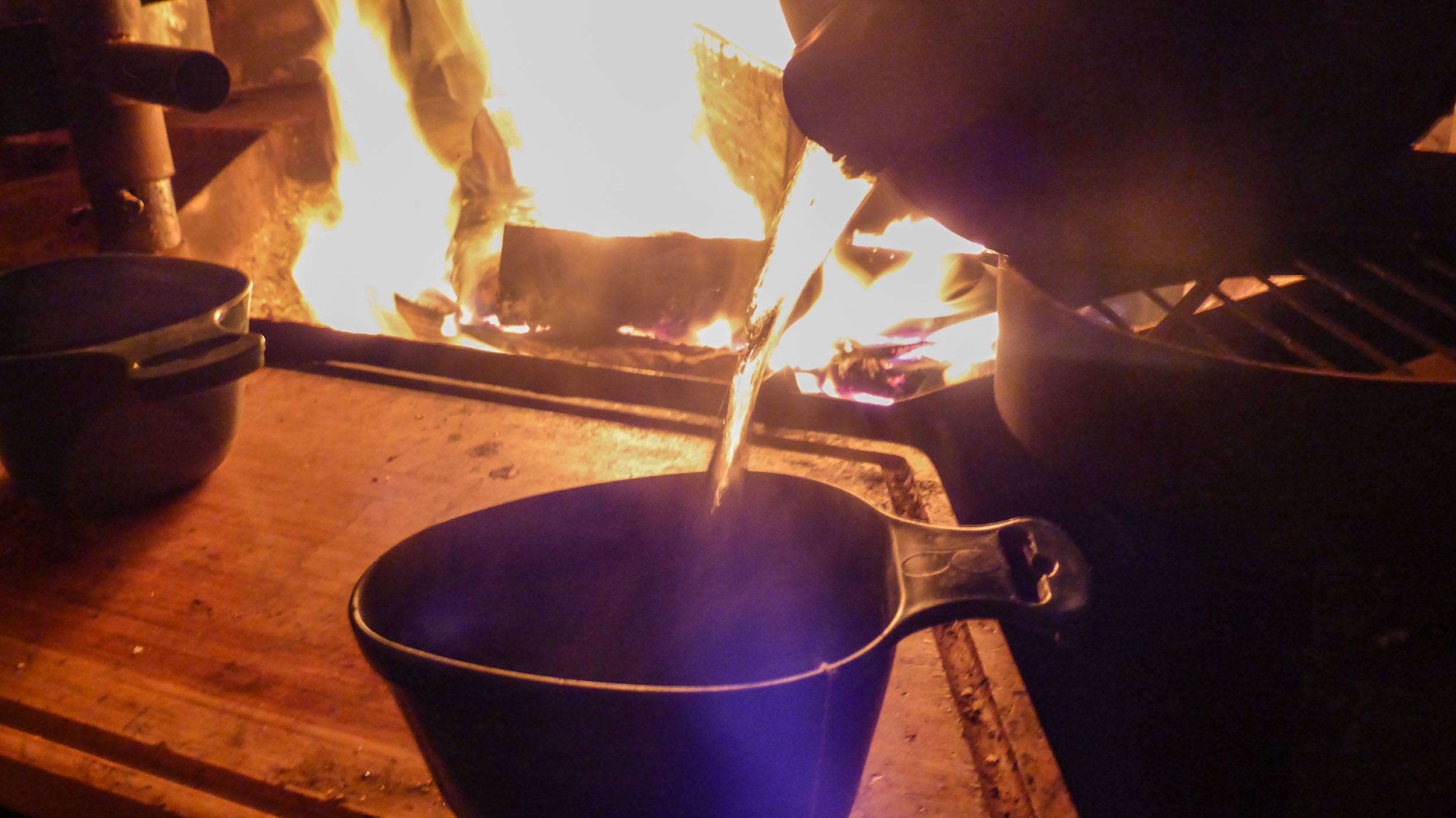 Boiling water being poured into a cup inside a cabin at Camp Alta in Sweden