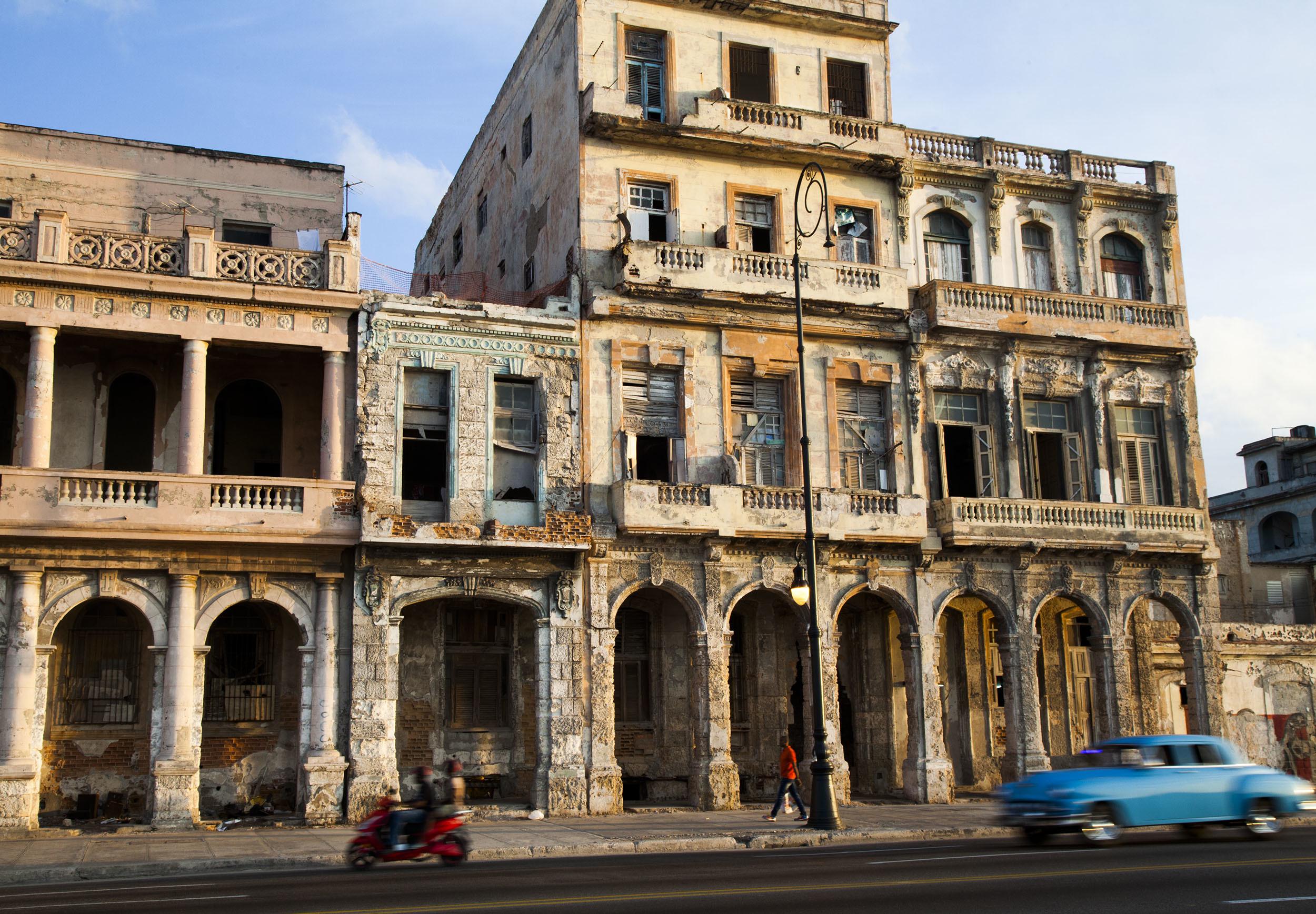 Classic car driving along El Malecon at dusk in Havana Cuba