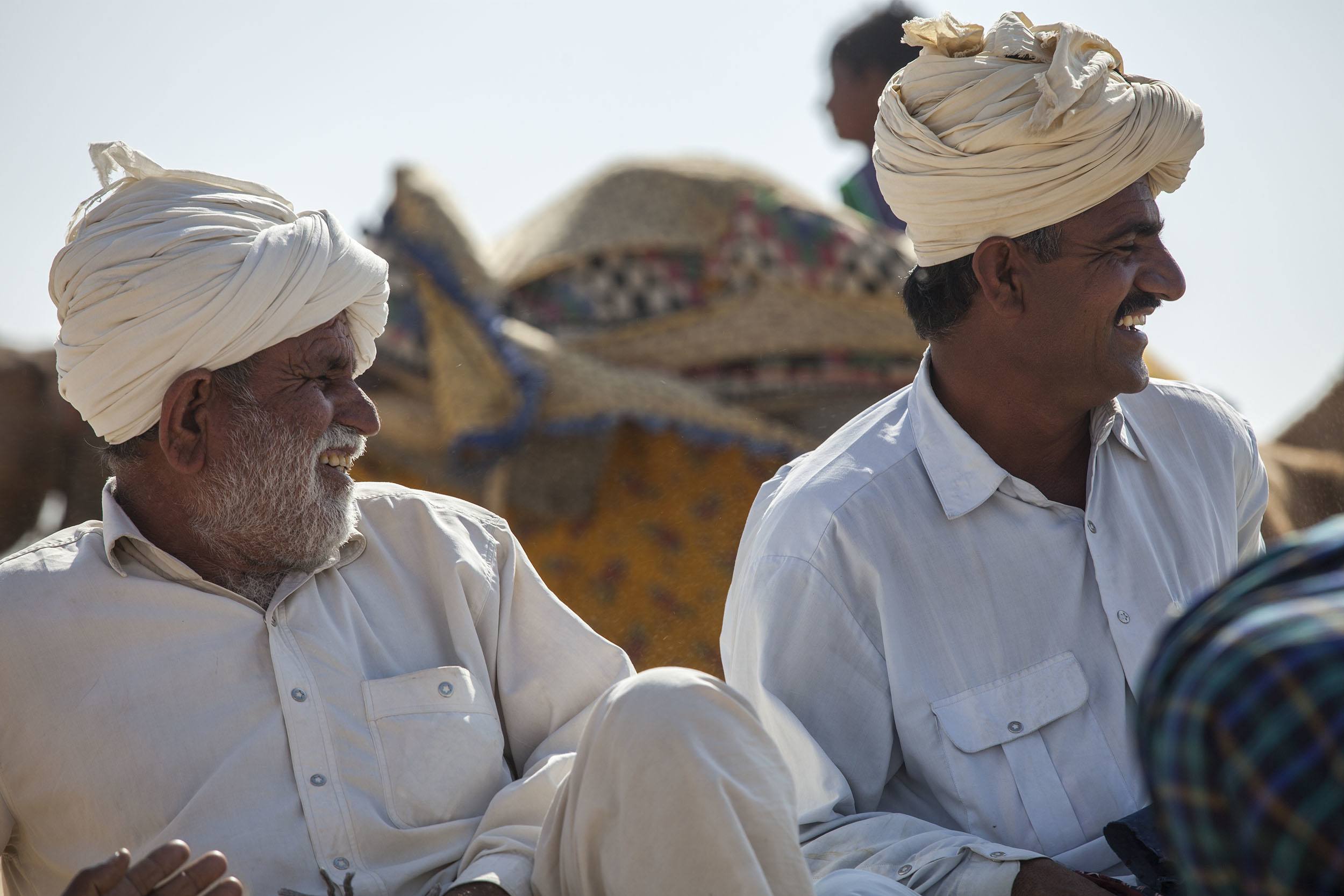 Indian men wearing turbans sitting in the sand at the Jaisalmer Desert Festival in India