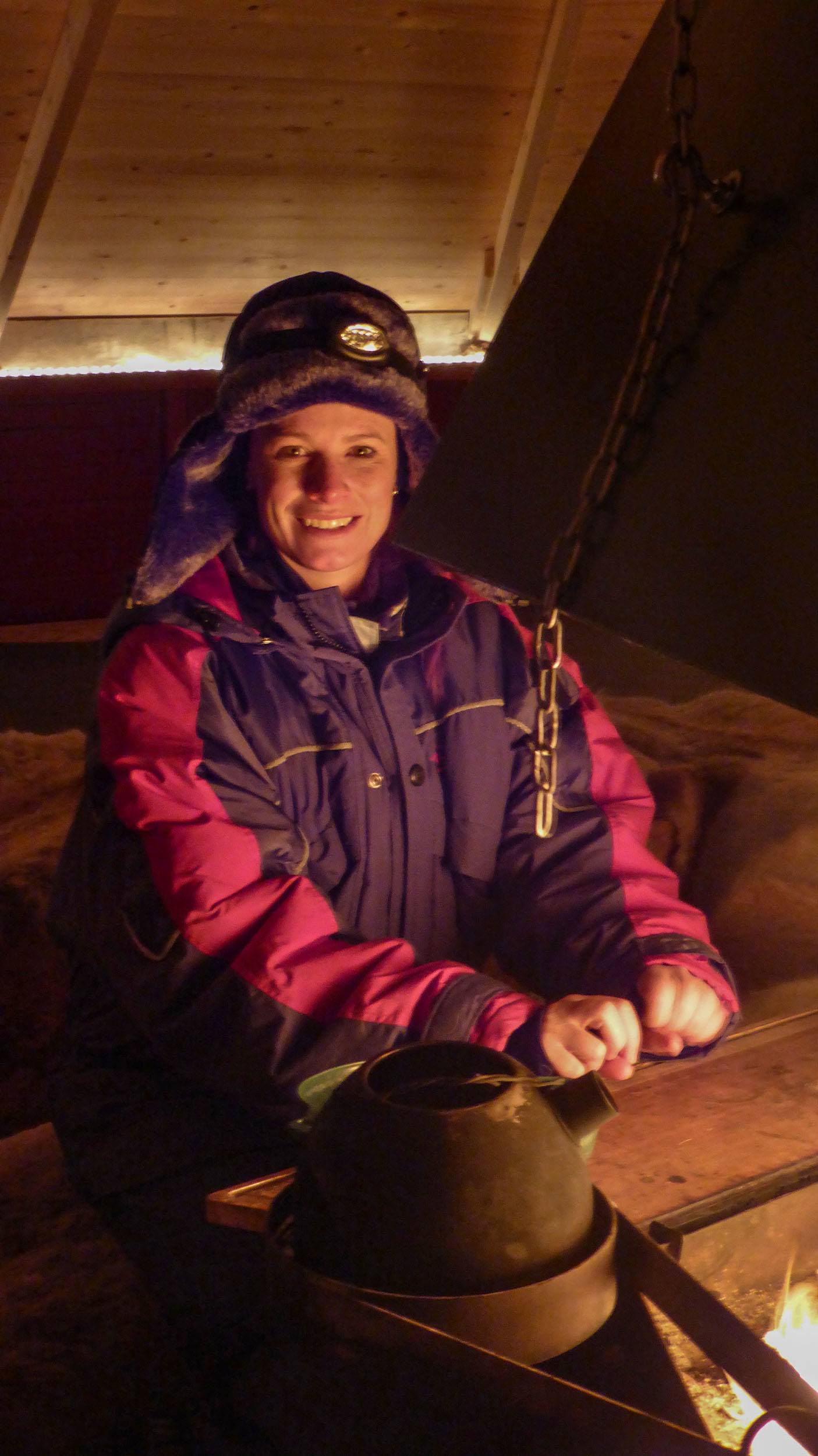 Kylie warming her hands by the fire at Camp Alta in Sweden