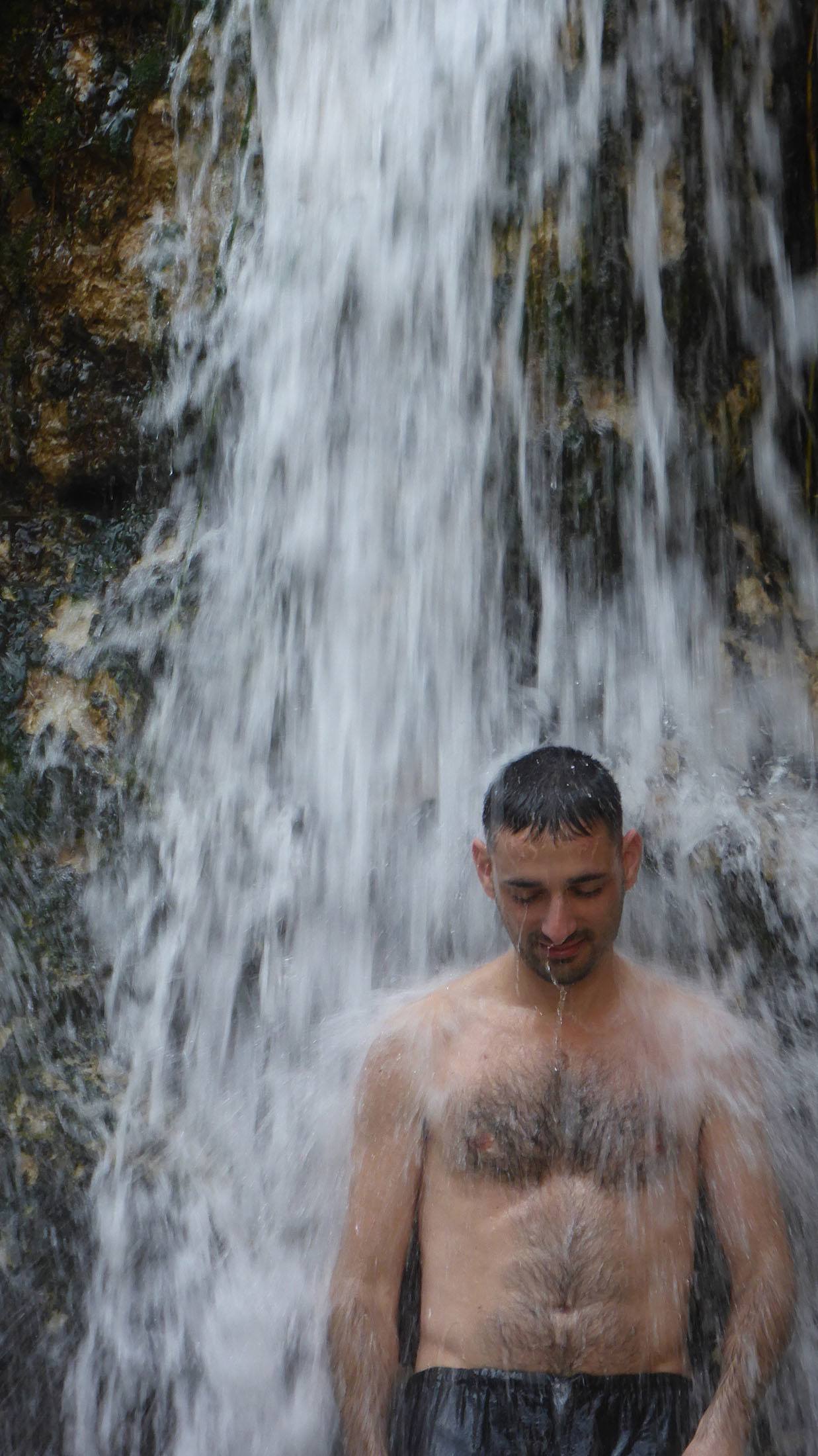 Man standing under waterfall near the Dead Sea Israel