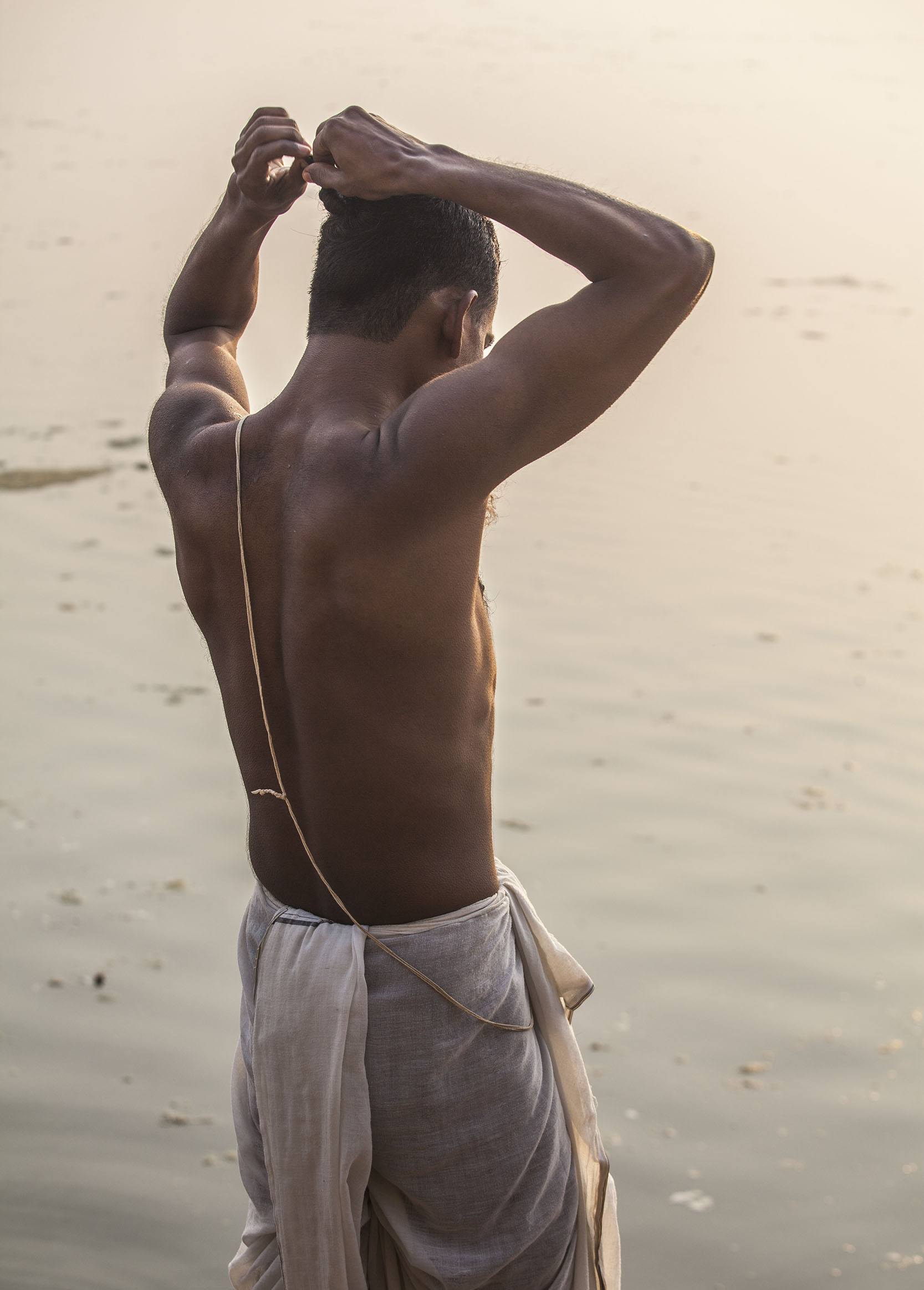 Man wearing a white lungi after bathing in the Ganges in Varanasi India