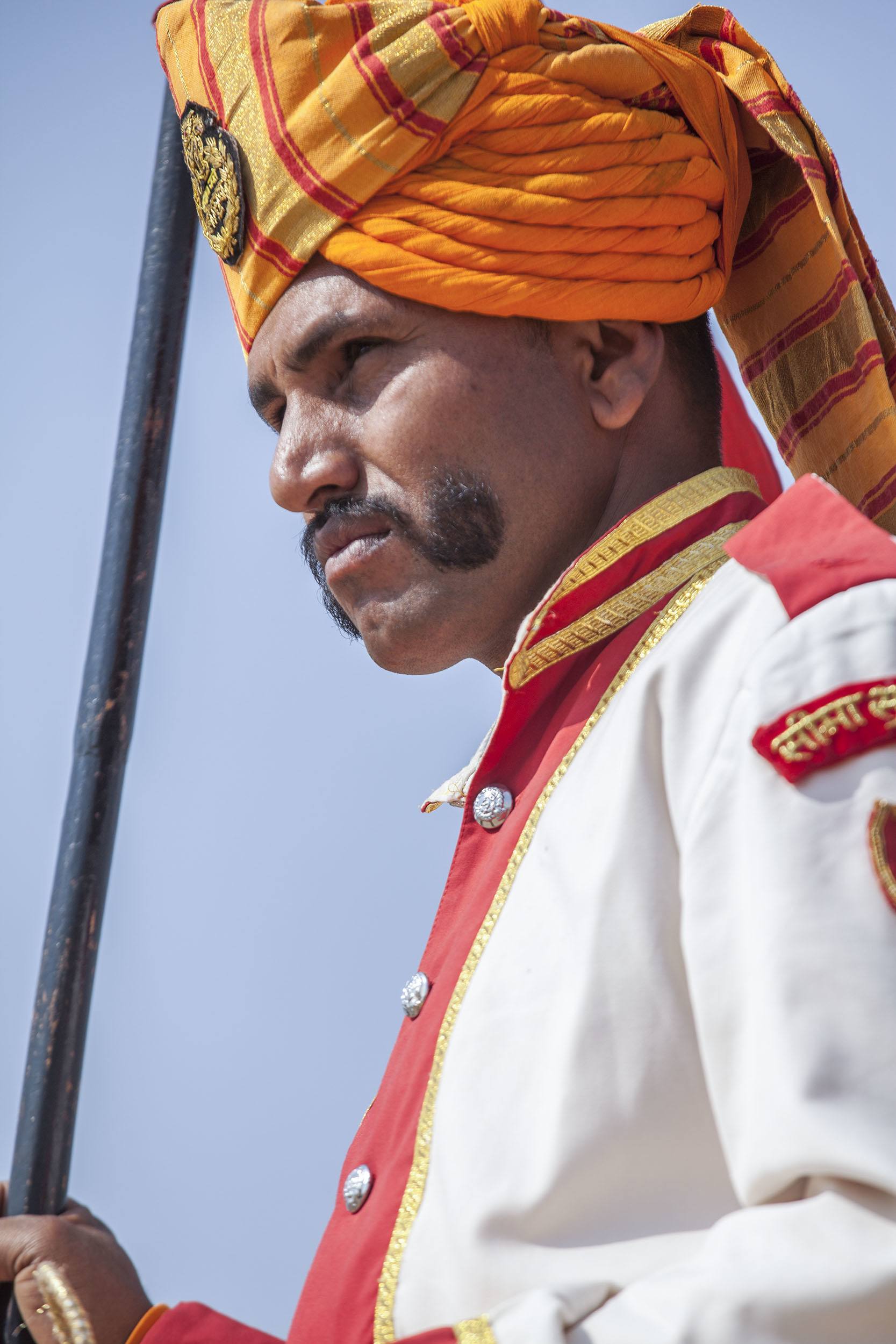 Men with decorative moustache and bright attire riding a camel in the Jaisalmer Desert Festival in India